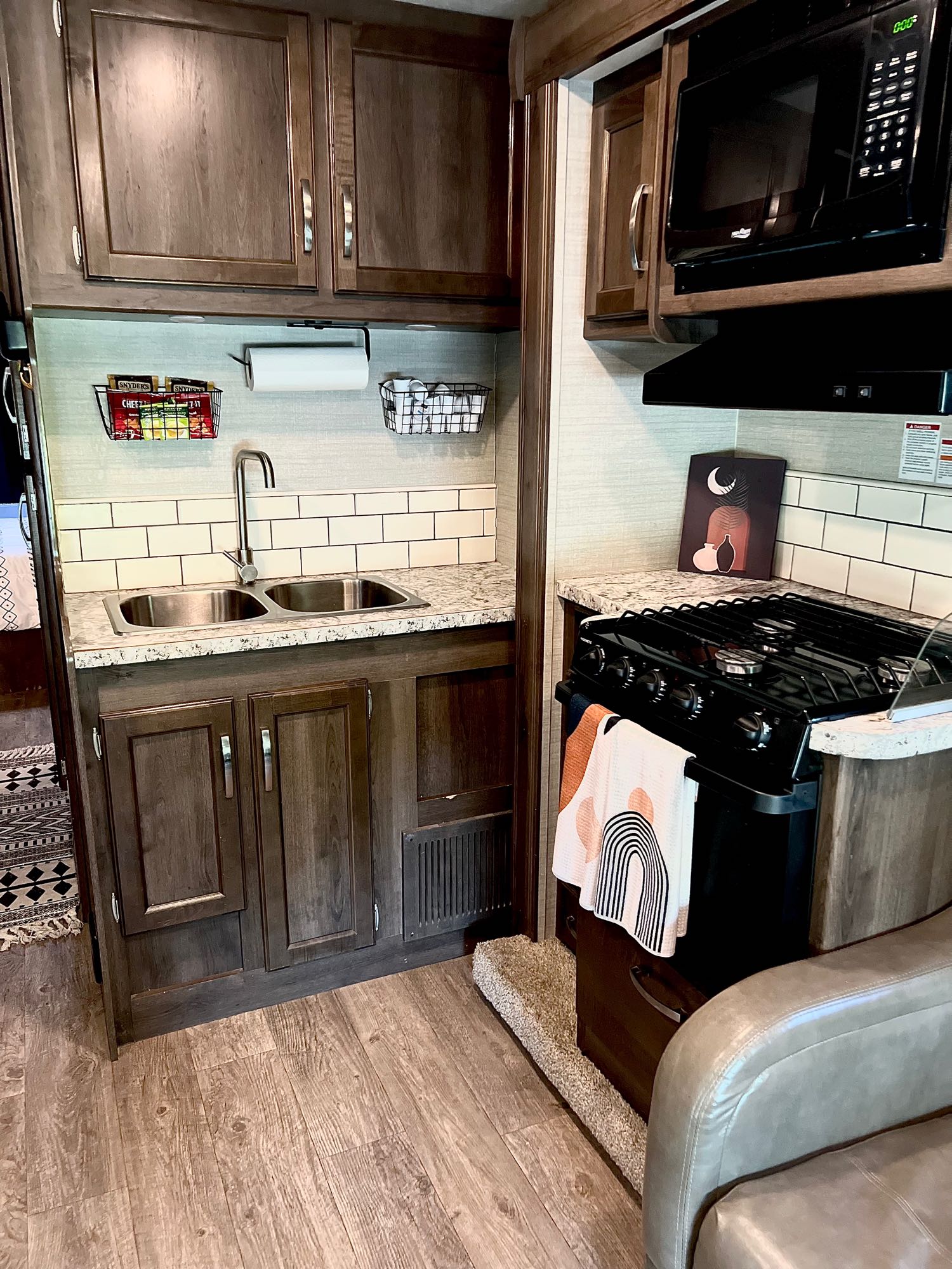 Modern RV rental kitchen interior with double sink, stove, microwave, and sleek wood cabinets for compact living.. Jayco Redhawk 2018