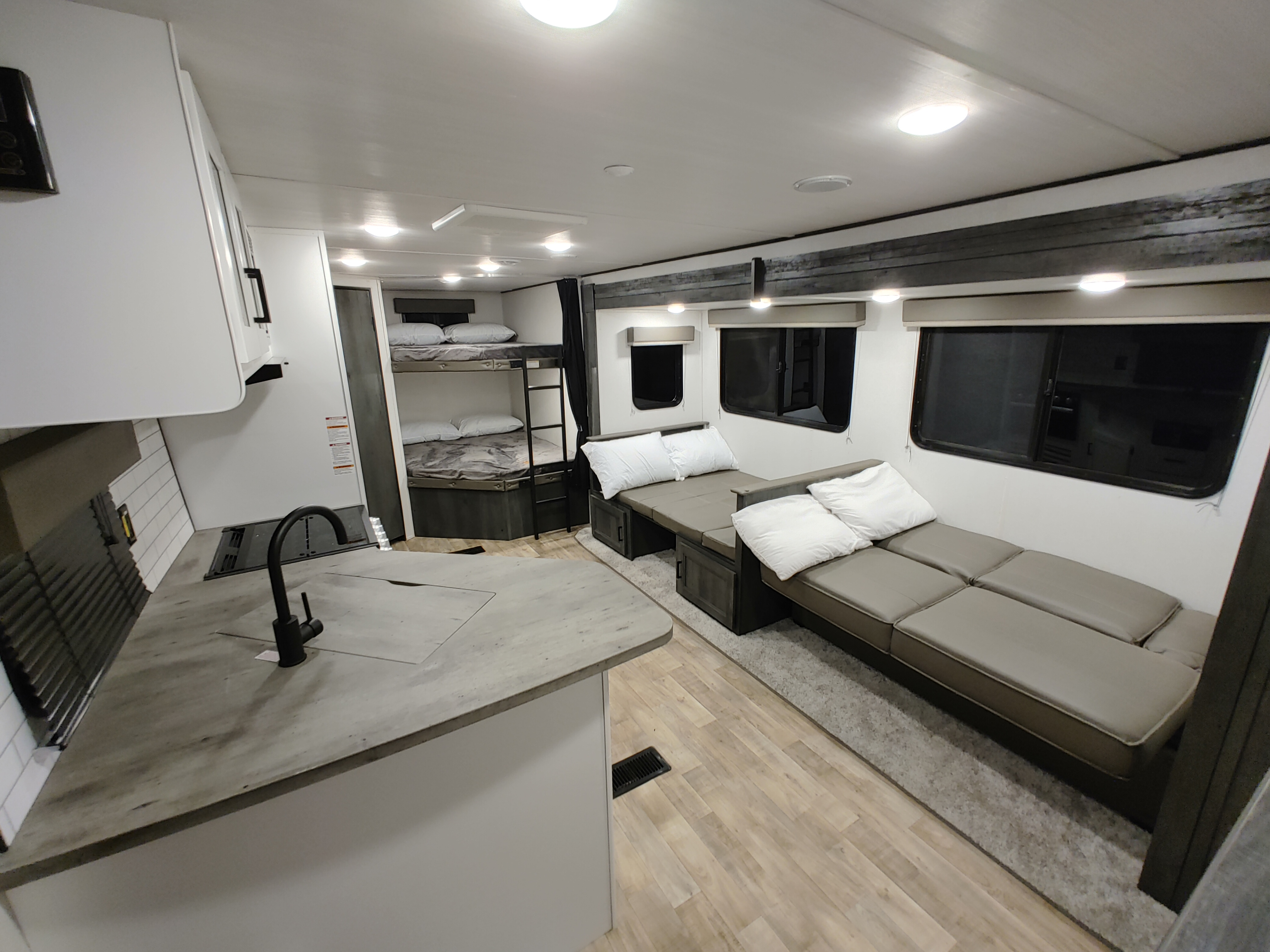 Spacious RV rental interior with a modern kitchen, cozy bunk beds, and a convertible lounge.. Keystone RV Hideout 2023