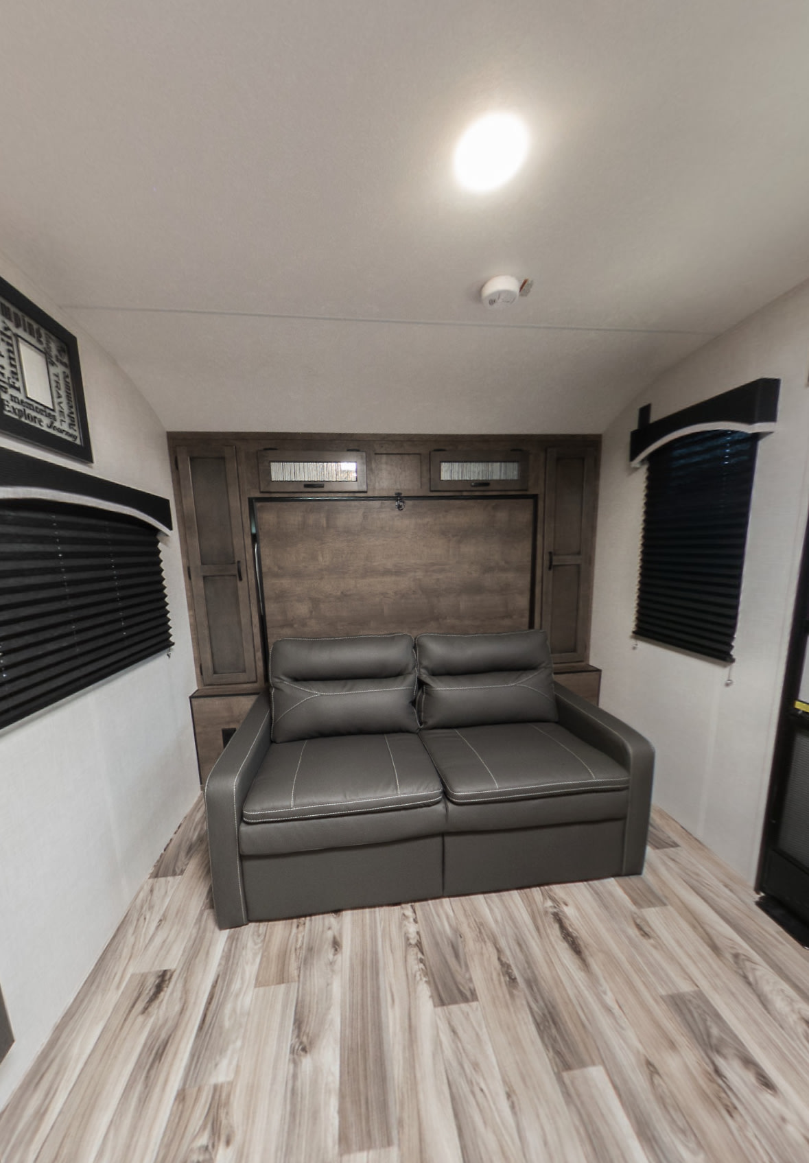 RV rental: Compact living space with a gray sofa & integrated Murphy bed. Features wall cabinets, blinds & wood-look floor.. Venture Sonic 2024
