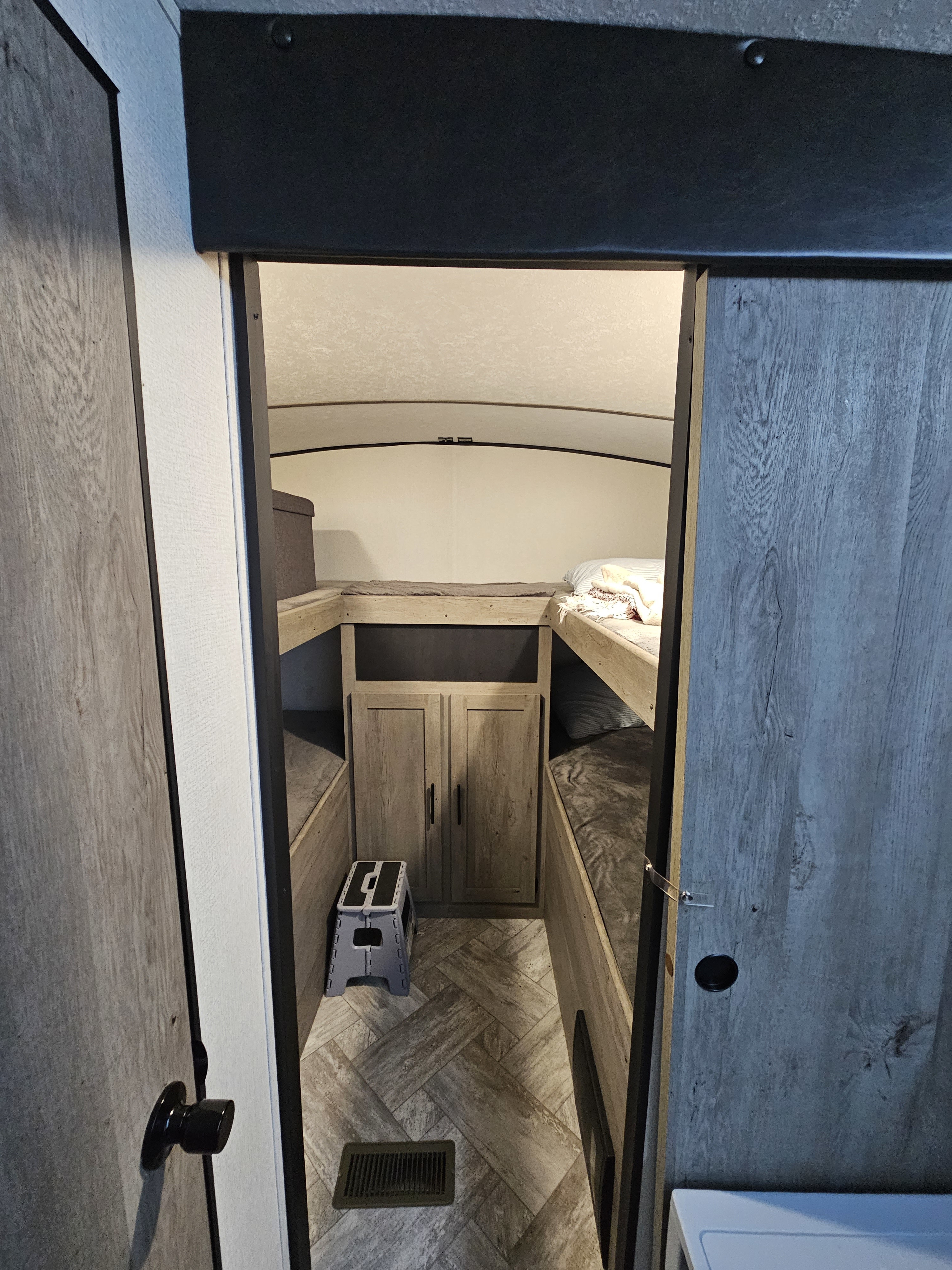 Inside an RV rental: cozy bunk beds, a cabinet, and step stool, ideal for compact travel living.. Keystone RV Springdale 2021
