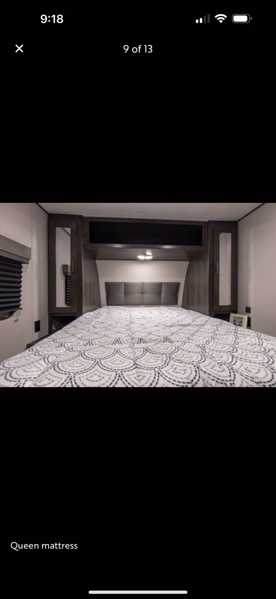 RV rental bedroom showcasing a queen bed with patterned comforter, upholstered headboard, and built-in cabinetry.. Grand Design Transcend Xplor 2021