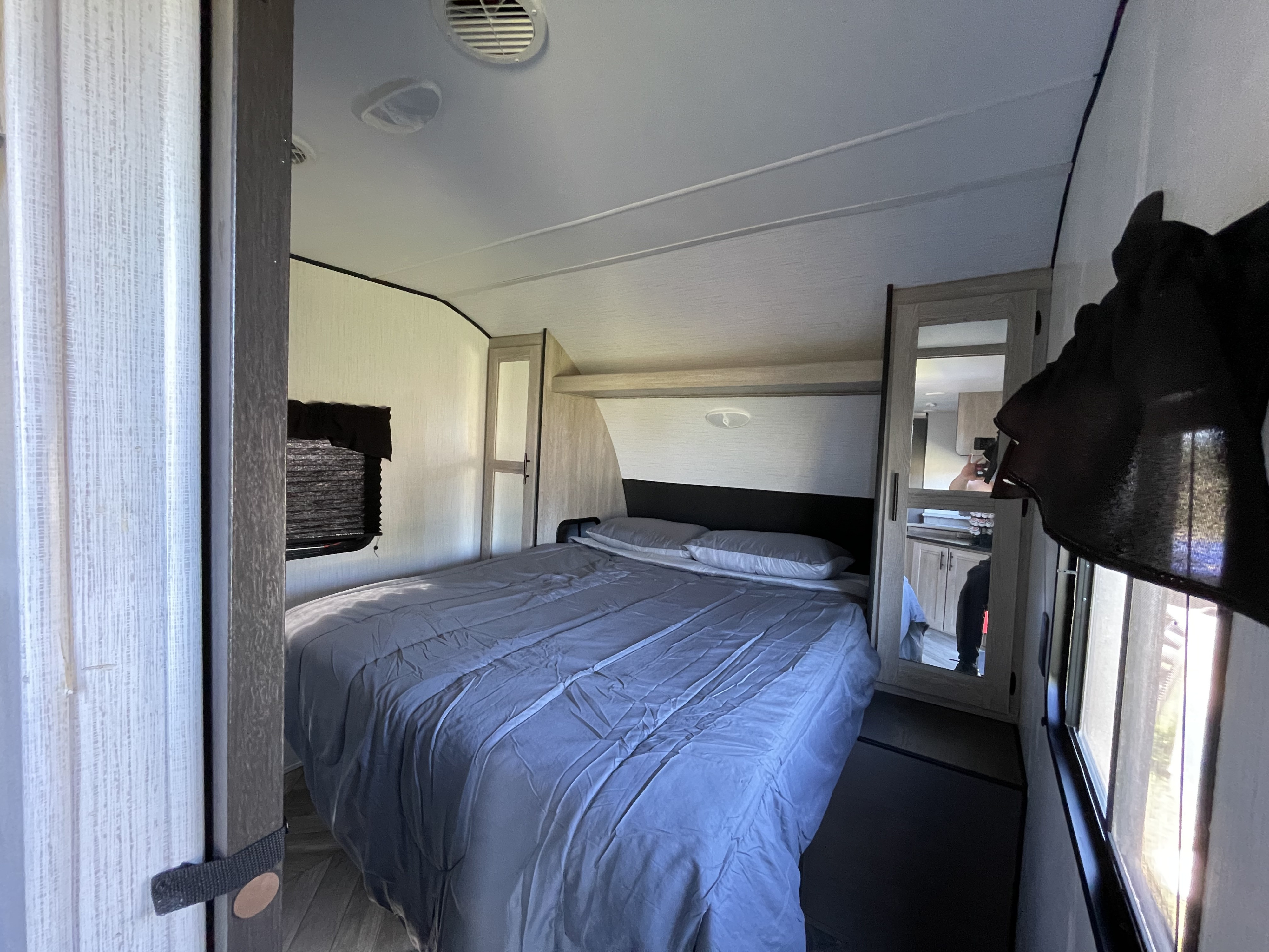 Cozy RV rental bedroom with a comfy bed, window, and mirrored closet. Perfect for travel adventures.. Heartland RVs Prowler 2022