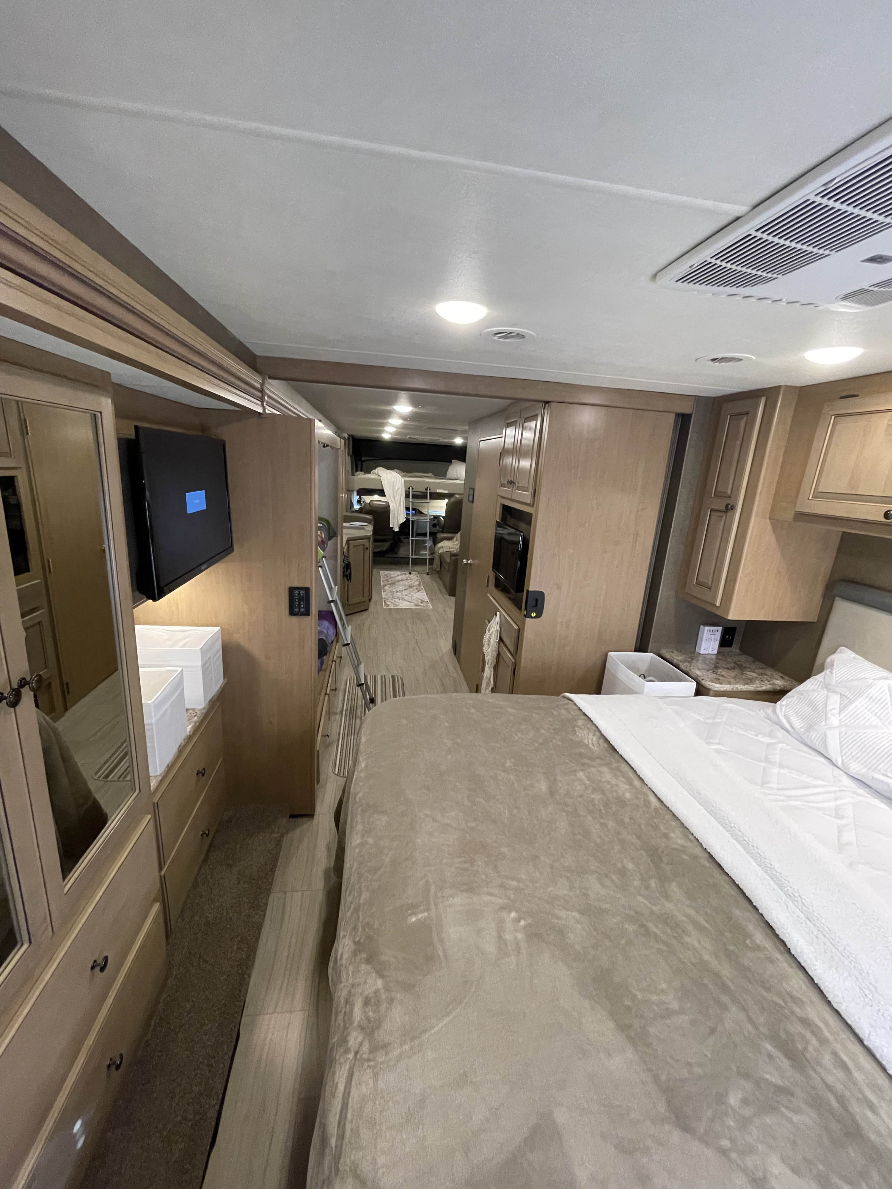 Modern RV rental interior featuring a bedroom area with TV, and a view into the front living space.. Thor Windsport 2019