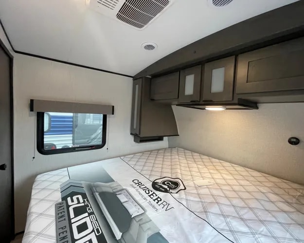 Comfortable RV rental bedroom with a large bed, overhead storage, side window, and modern ceiling vents.. Cruiser RV MPG Ultra Lite 2022