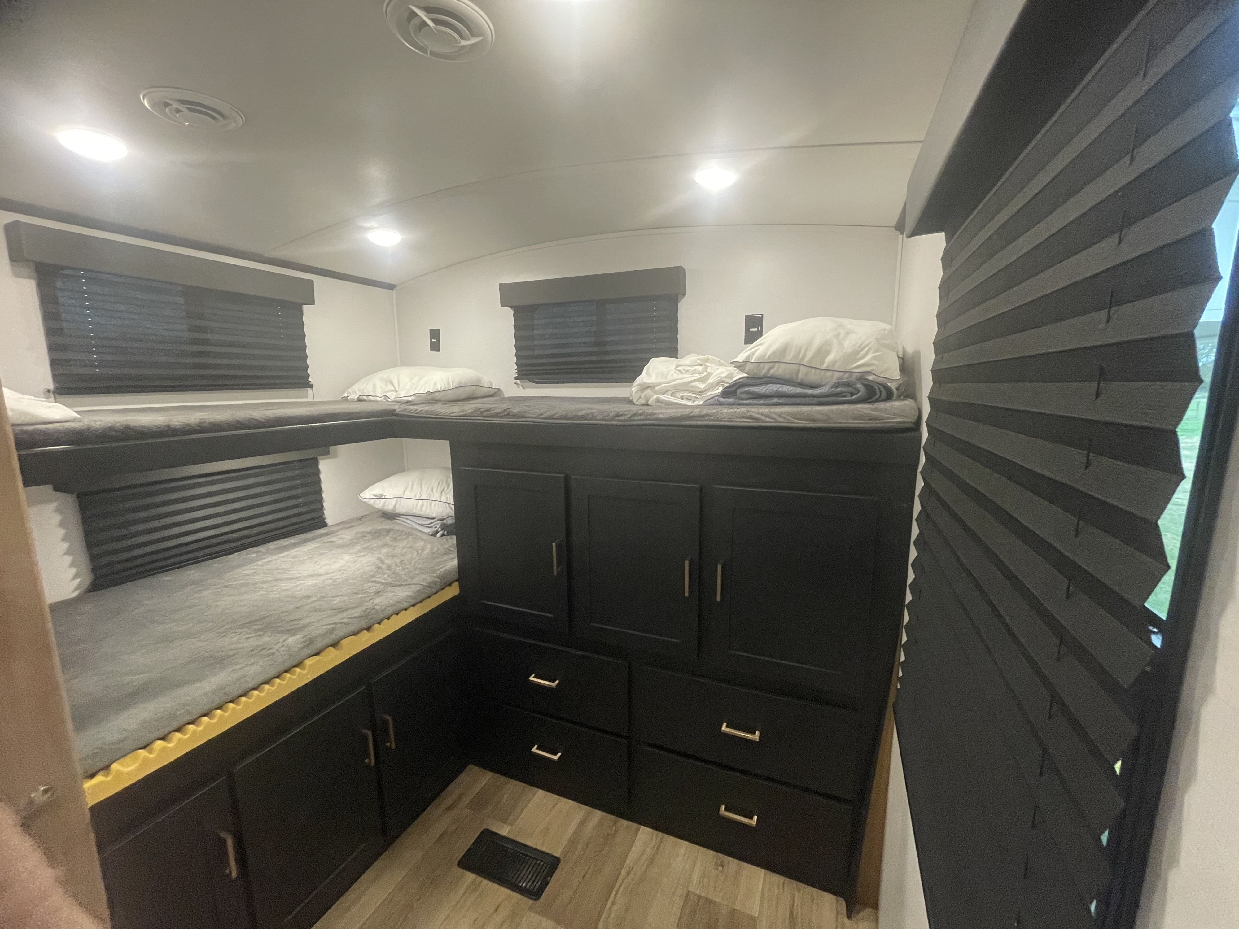 Spacious RV rental interior featuring comfortable bunk beds with grey bedding, built-in storage, and blackout blinds.. Keystone Outback 2022