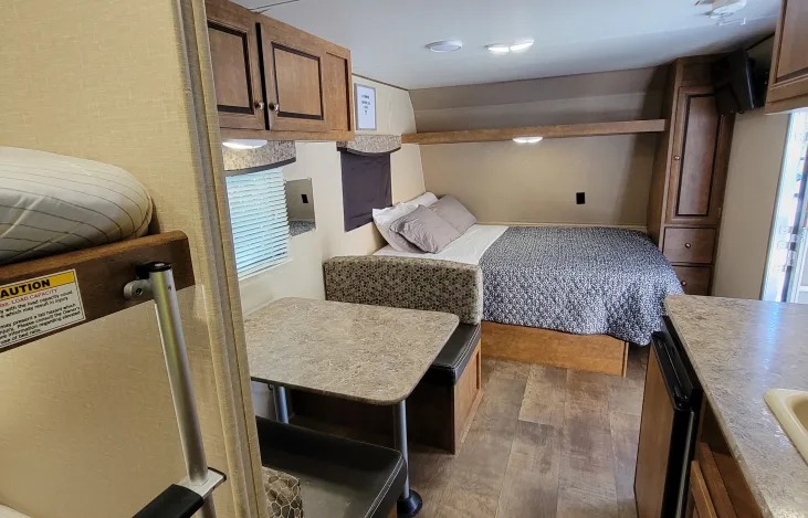 This RV rental interior offers a bed, a small dinette with bench seating, and a bunk bed, plus a mini-kitchen area.. Crossroads RV Z-1 Lite 2017