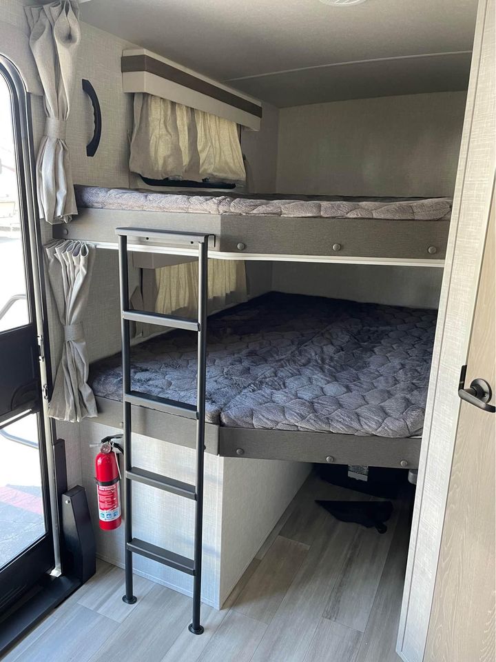 Inside this RV rental, comfortable bunk beds offer compact sleeping space with a ladder & fire extinguisher for travel adventures.. Forest River Rockwood Ultra Lite 2022