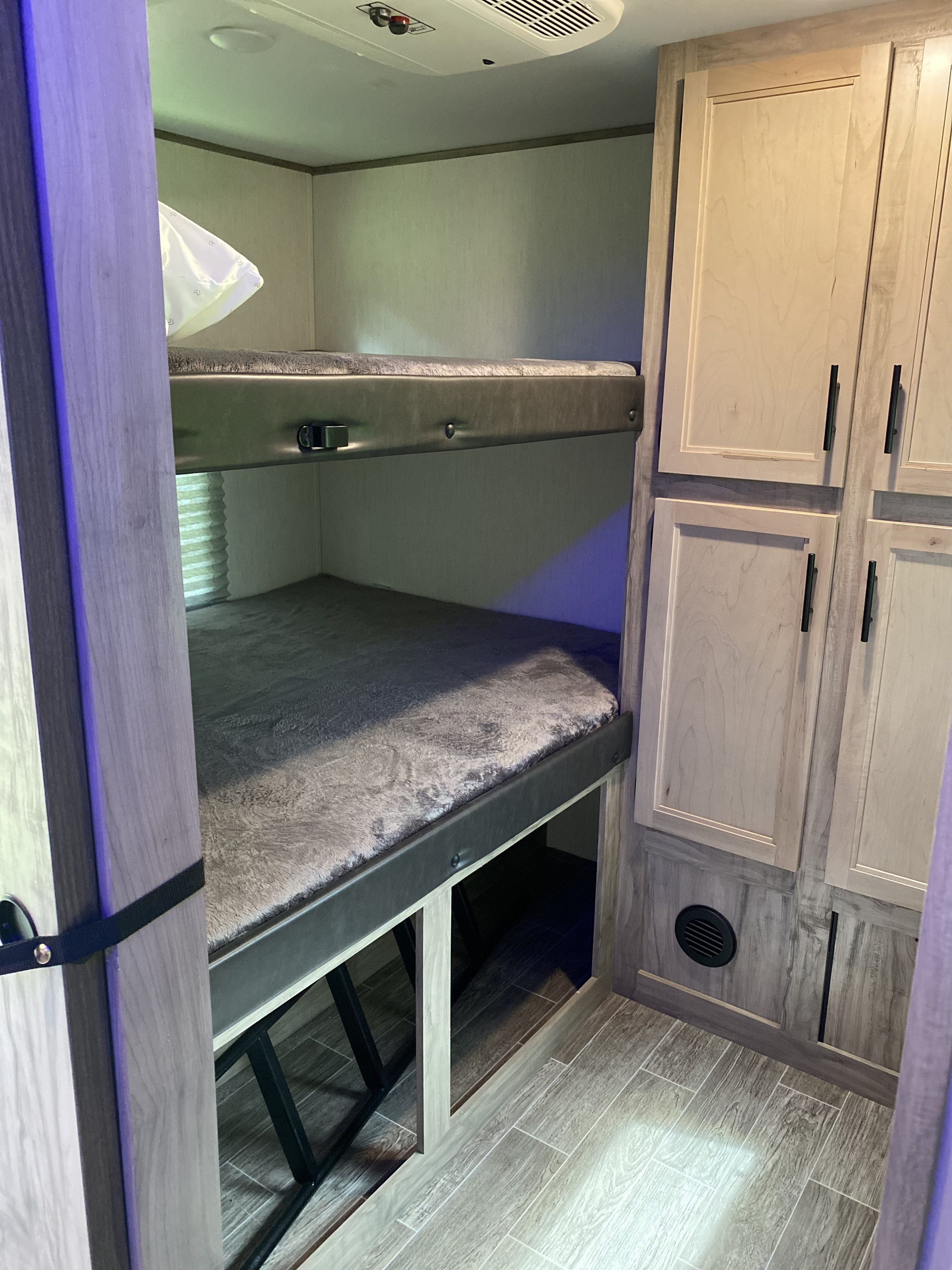 Cozy RV rental interior with bunk beds, built-in storage cabinets, and plush bedding, ideal for family trips.. Forest River Cherokee Alpha Wolf 2022