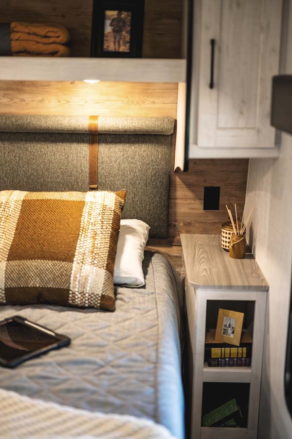 Relax in this modern RV rental bedroom, offering a comfortable bed, stylish headboard, and convenient bedside amenities.. Heartland RVs Milestone 2023