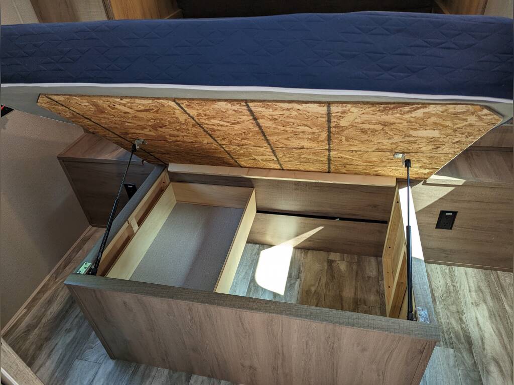 RV rental under-bed storage with mattress lifted by gas struts, revealing efficient space for belongings.. Grand Design Imagine XLS 2023