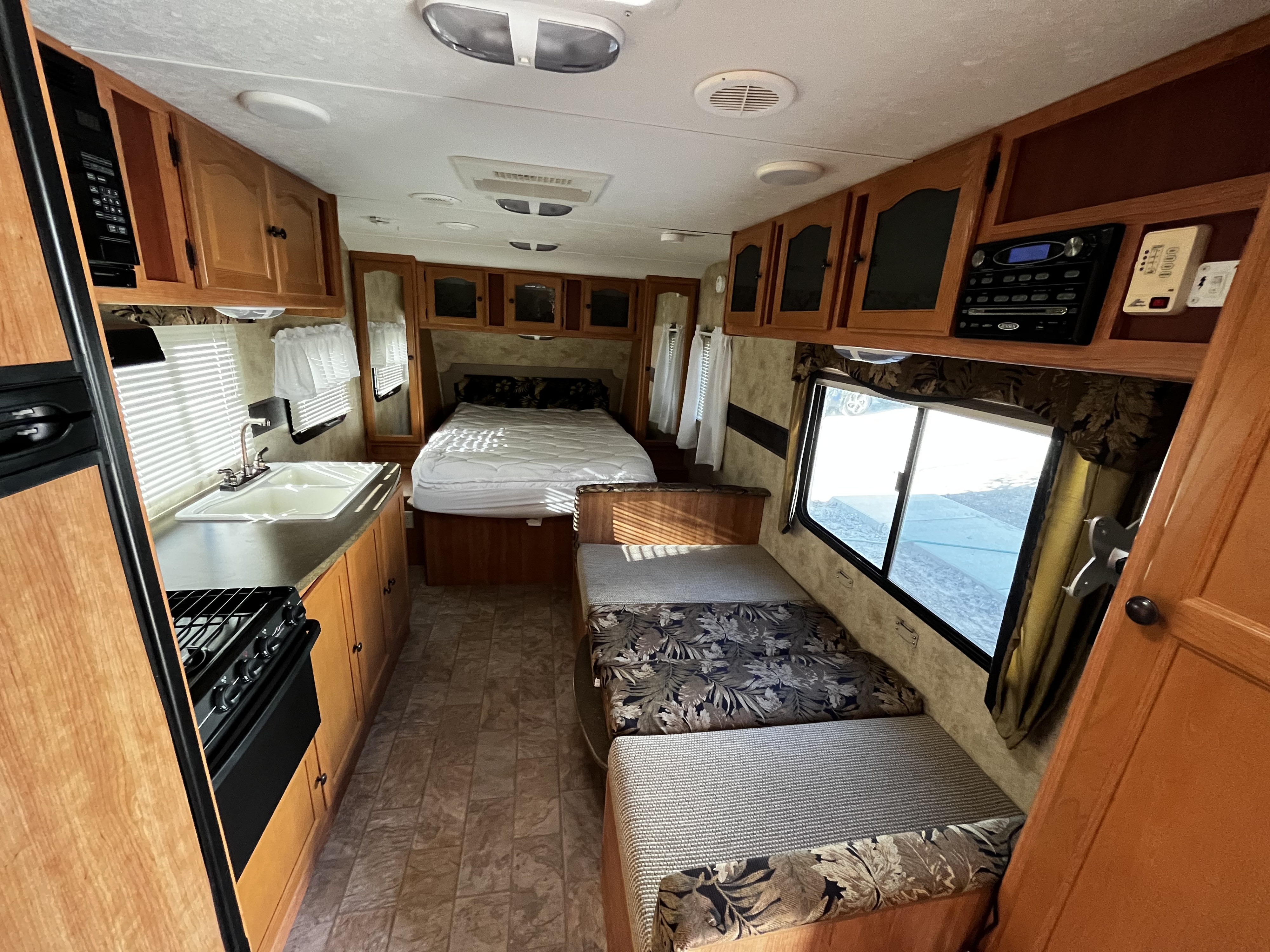 Inside this cozy rv rental: full kitchen, comfy bed, and dining area.. Keystone RV Passport Ultra Lite 2010