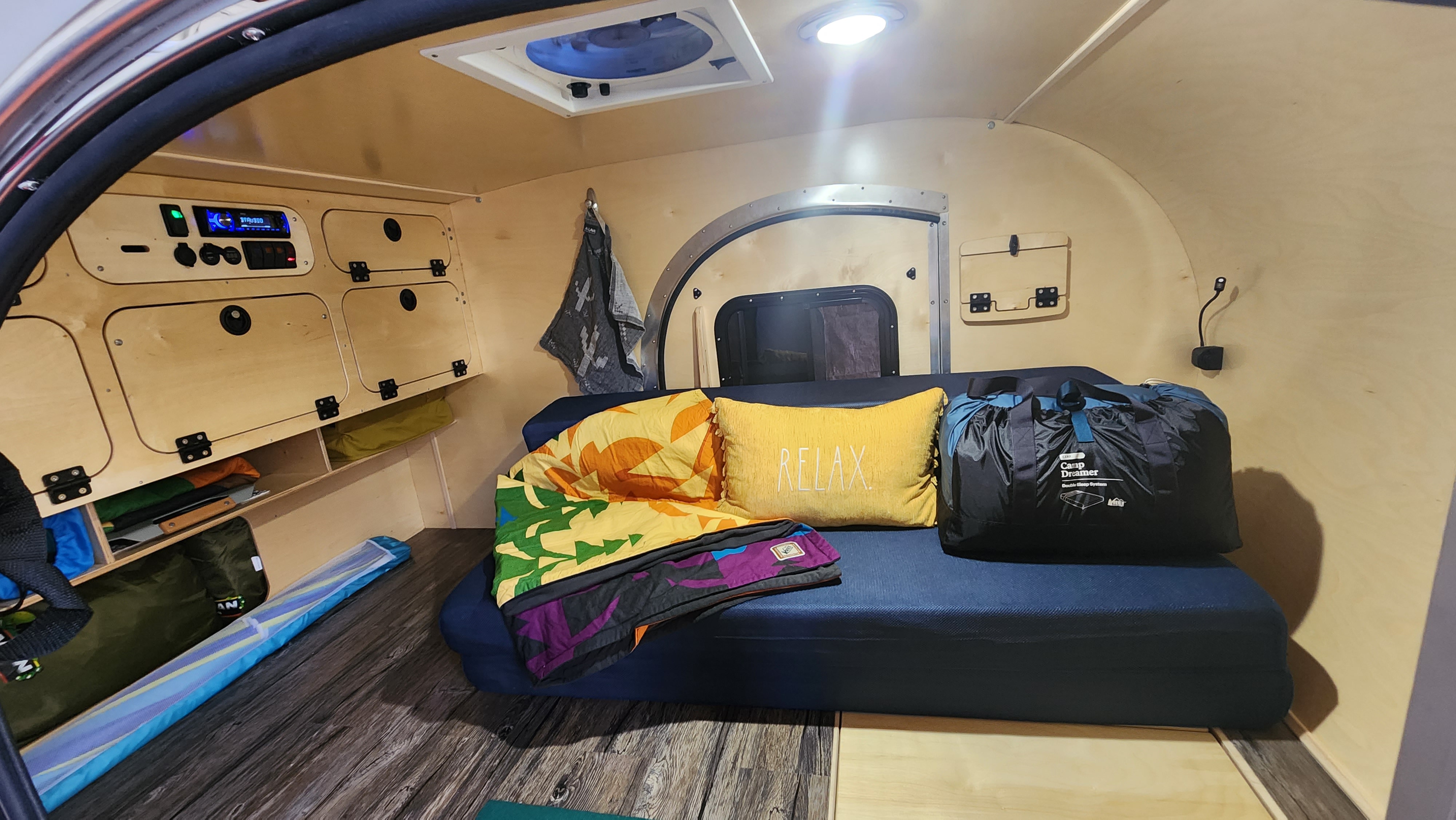 Explore this RV rental's cozy teardrop camper interior: comfy bed, ample storage, and tech panel for camping comfort.. SoCal Teardrop 511XS 2023