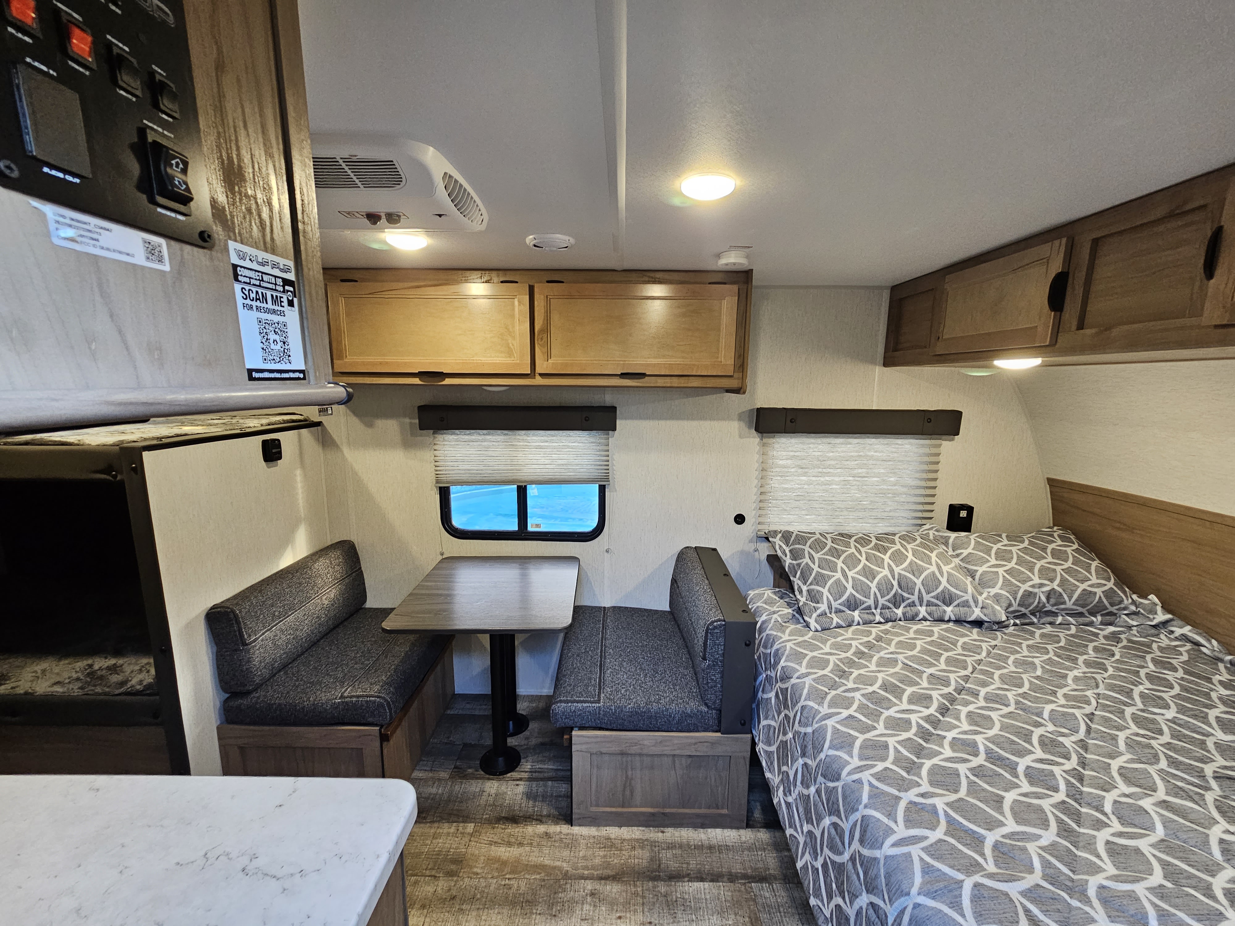 RV rental interior with a comfy bed, dinette, overhead storage, and AC unit for a perfect getaway.. Forest River Cherokee Wolf Pup 2024