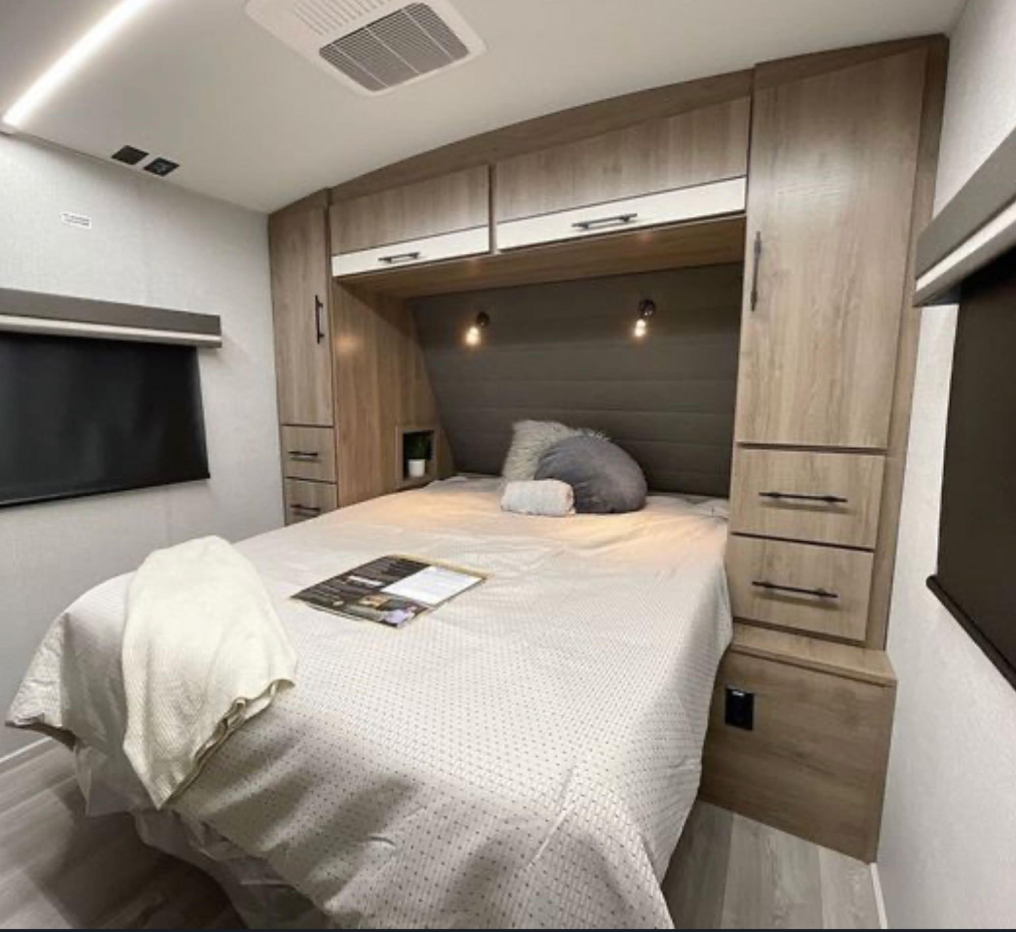 Cozy RV rental bedroom with a large bed, built-in storage, and ambient lighting for a comfortable stay.. Grand Design Imagine 2023