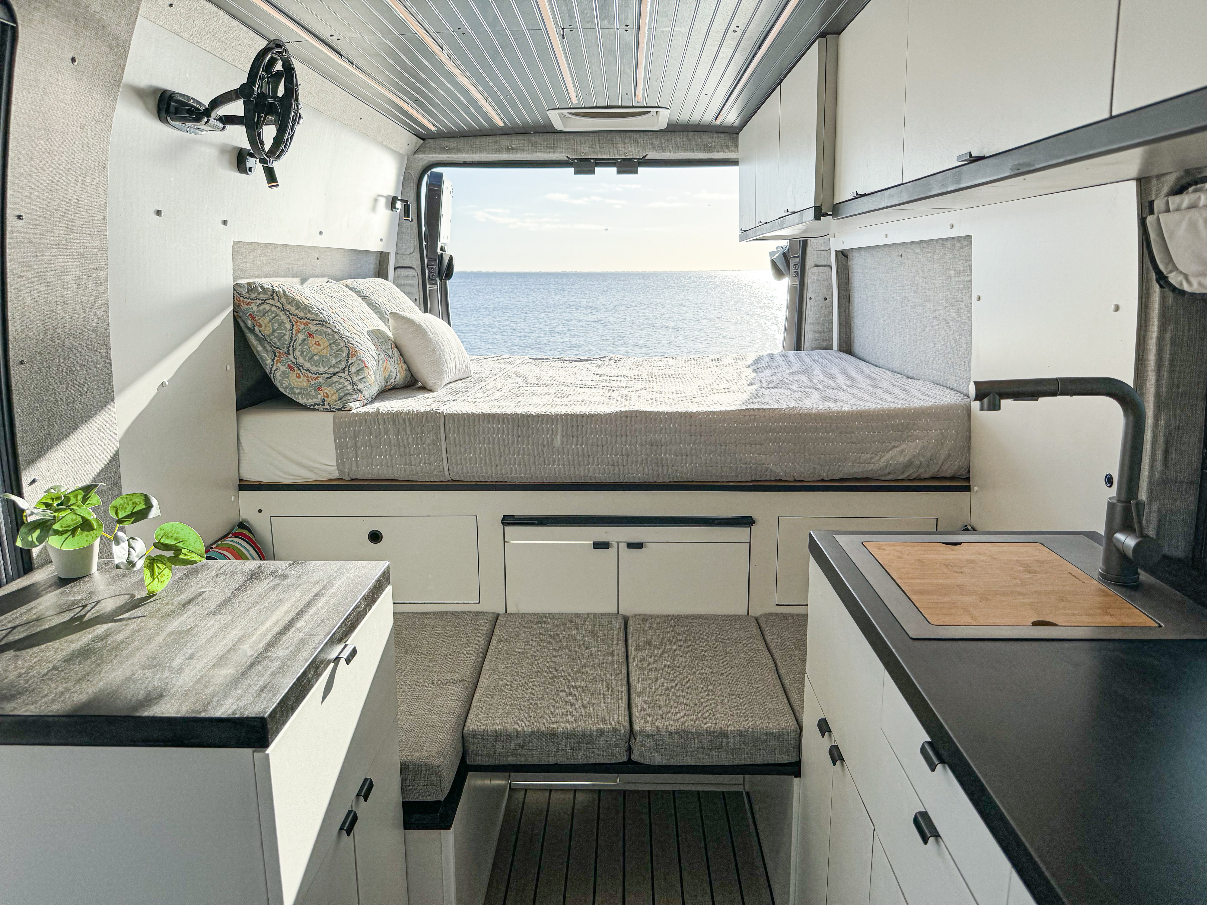 Spacious RV rental interior with a cozy bed, ocean view, modern kitchen, and comfortable living area.. Custom Built Other 2021