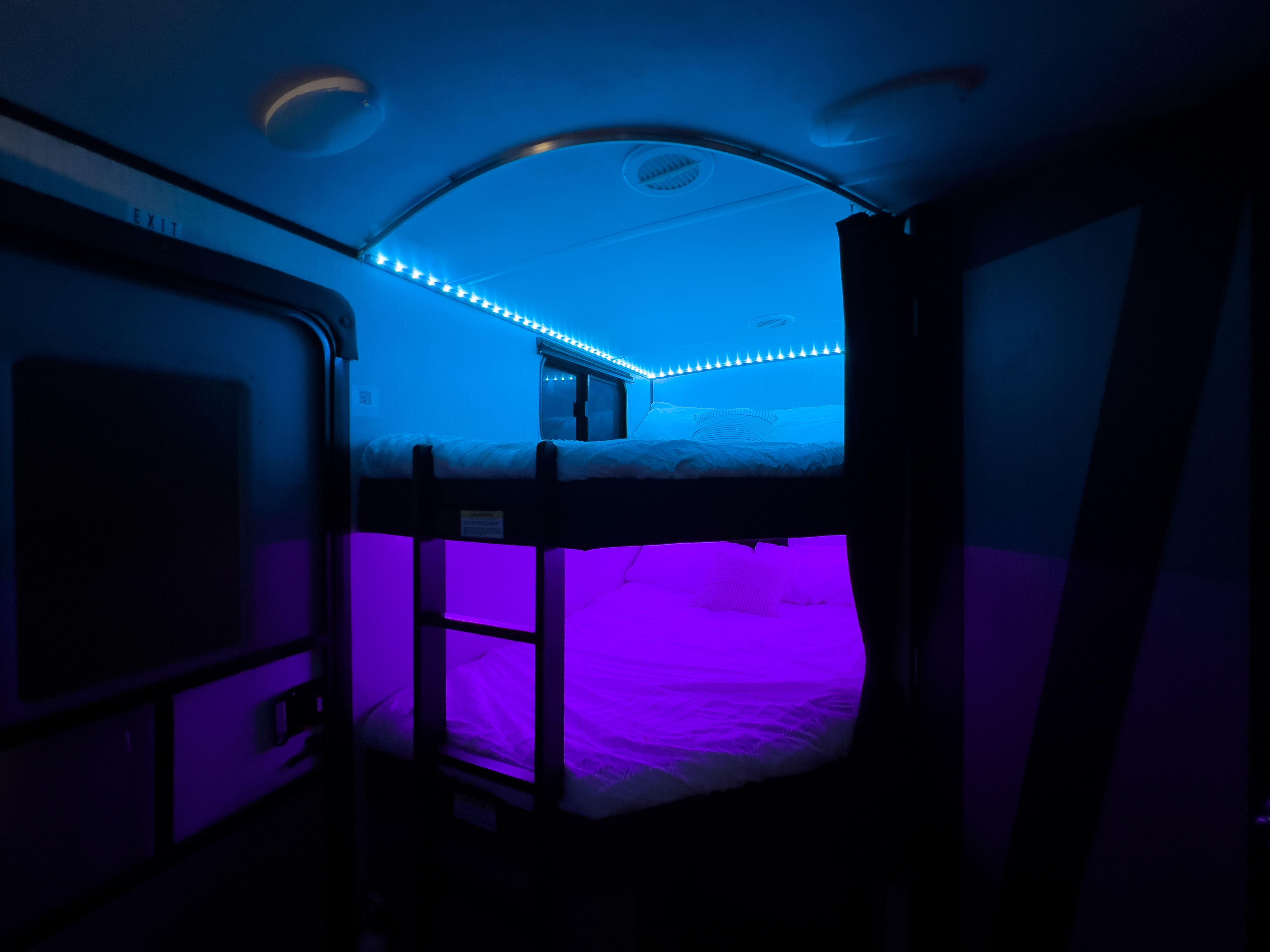 Cozy rv rental bunk beds with vibrant blue and purple LED lighting, creating a modern and inviting interior space.. Heartland RVs Mallard 2021
