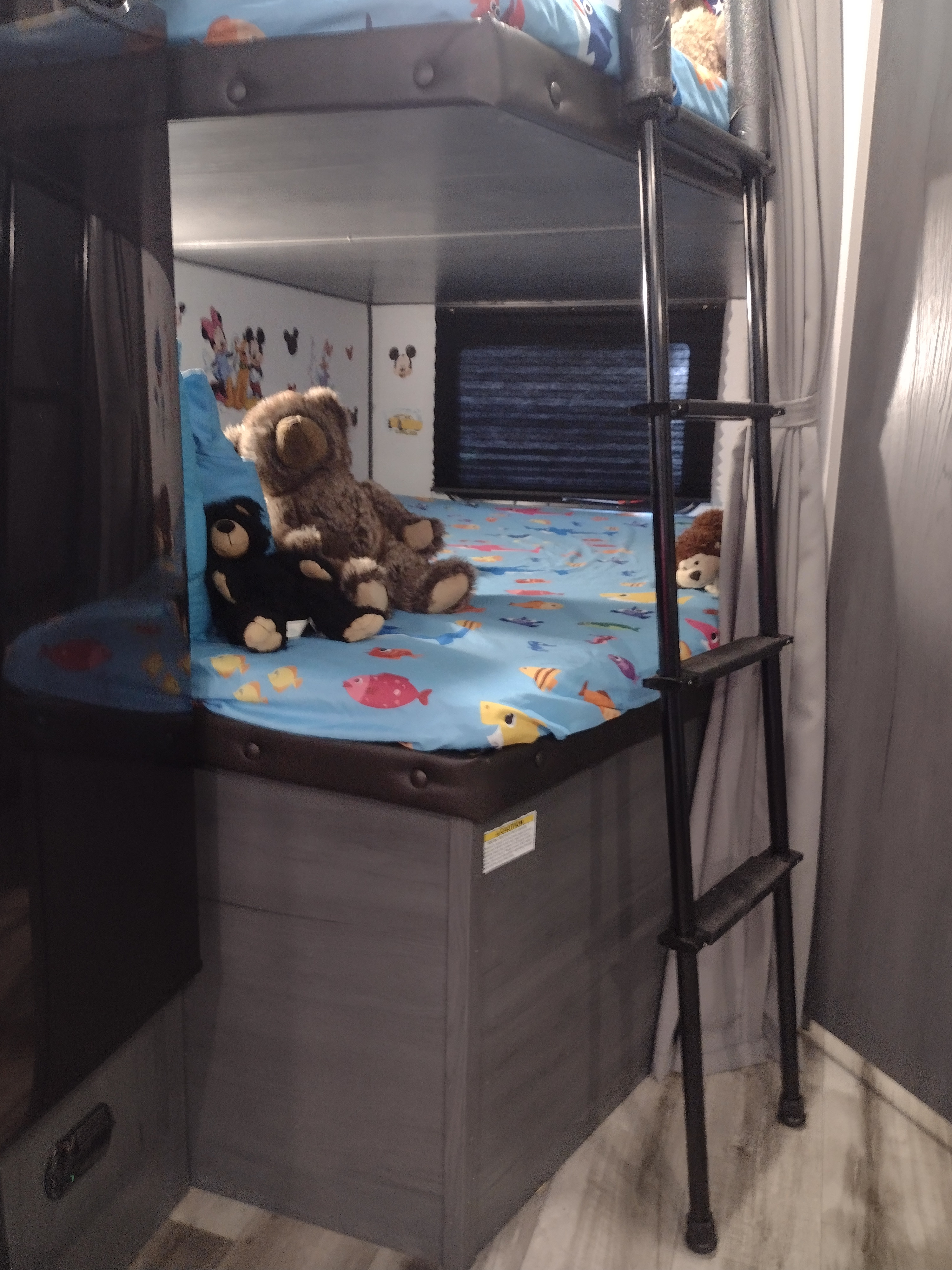 Kid-friendly RV rental bunk bed with stuffed animals, a fish sheet, and cartoon decals for a cozy stay.. Other Other 2024