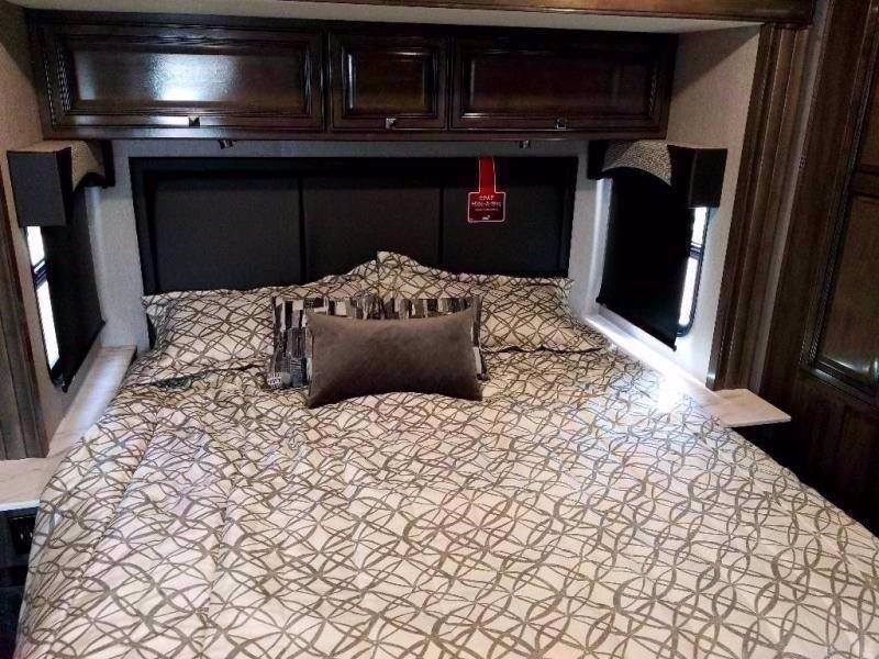 Cozy RV rental bedroom with patterned bedding, compact side windows, and ample overhead storage, ready for your trip.. Fleetwood Fortis 2021