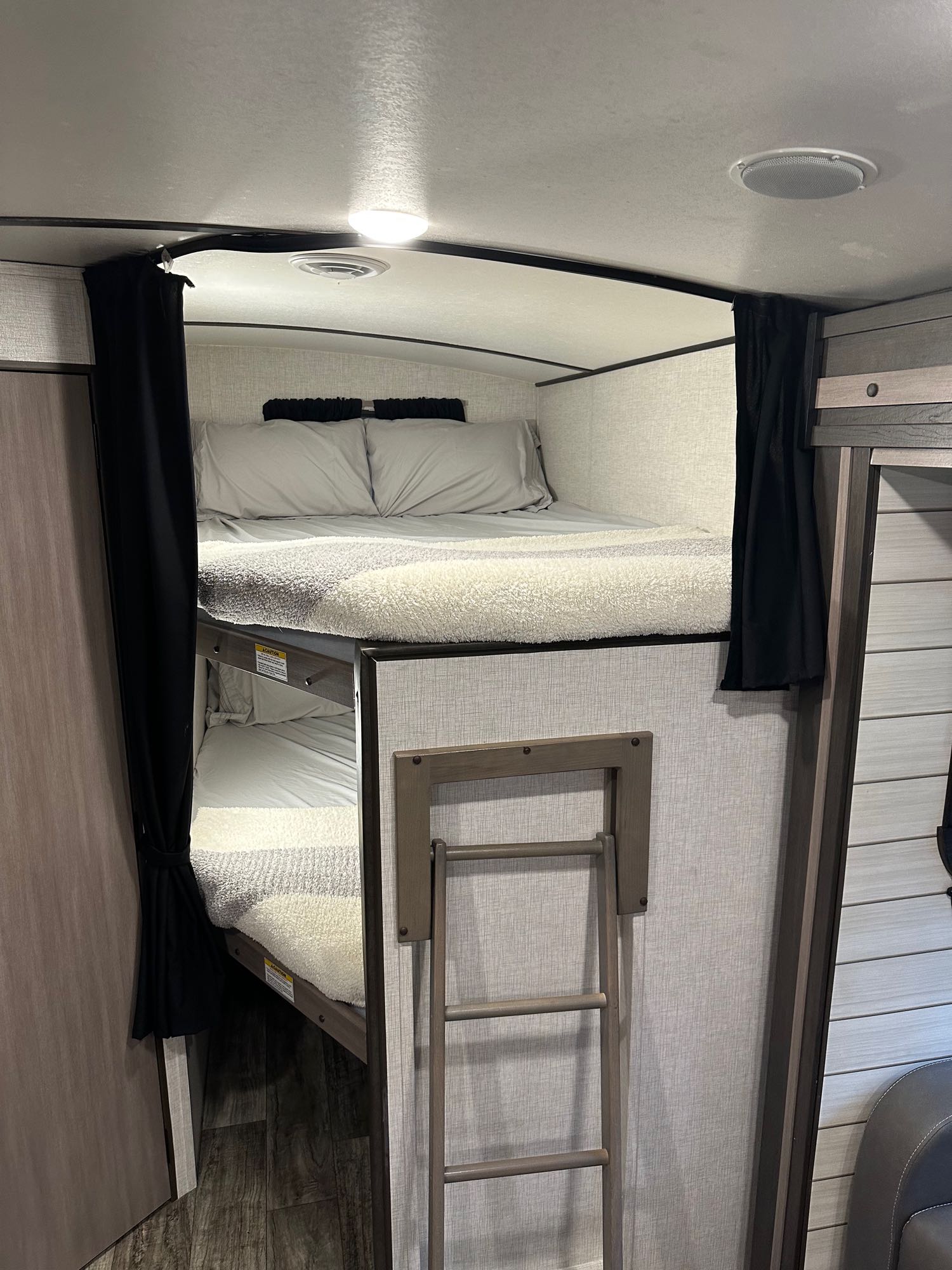 This RV rental features cozy bunk beds with privacy curtains and a ladder, ideal for a comfortable stay.. Crossroads RV Sunset Trail Super Lite 2021