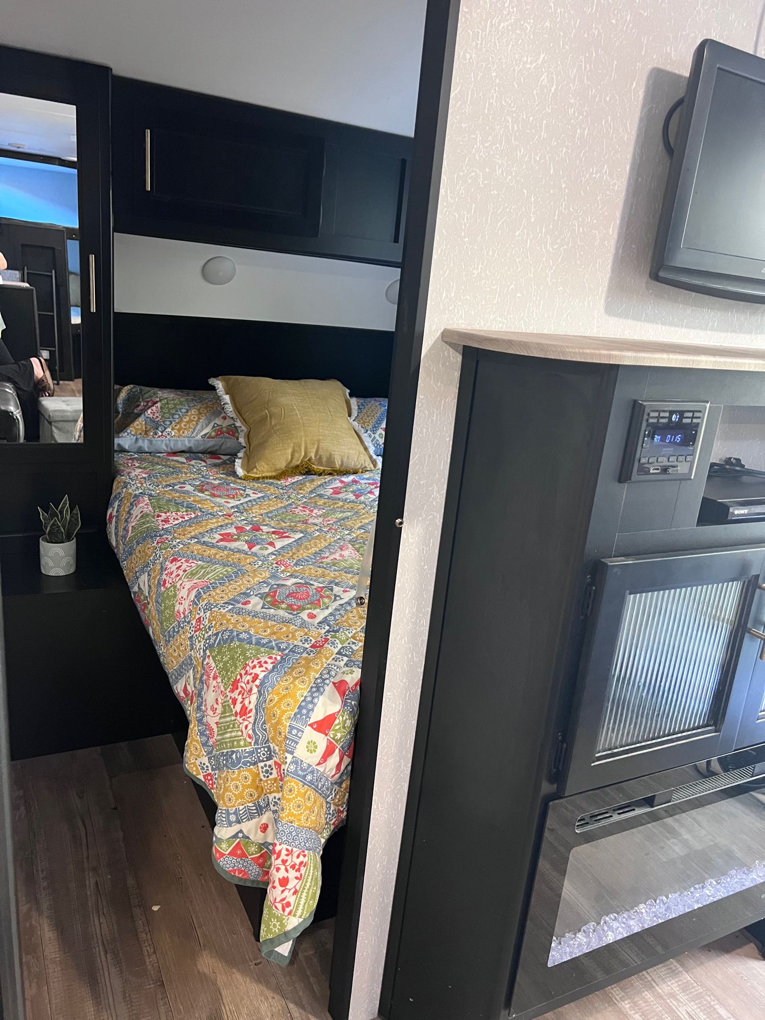 Cozy RV rental bedroom with colorful quilt, integrated entertainment system, and electric fireplace.. Forest River Cherokee Grey Wolf Black Label 2021