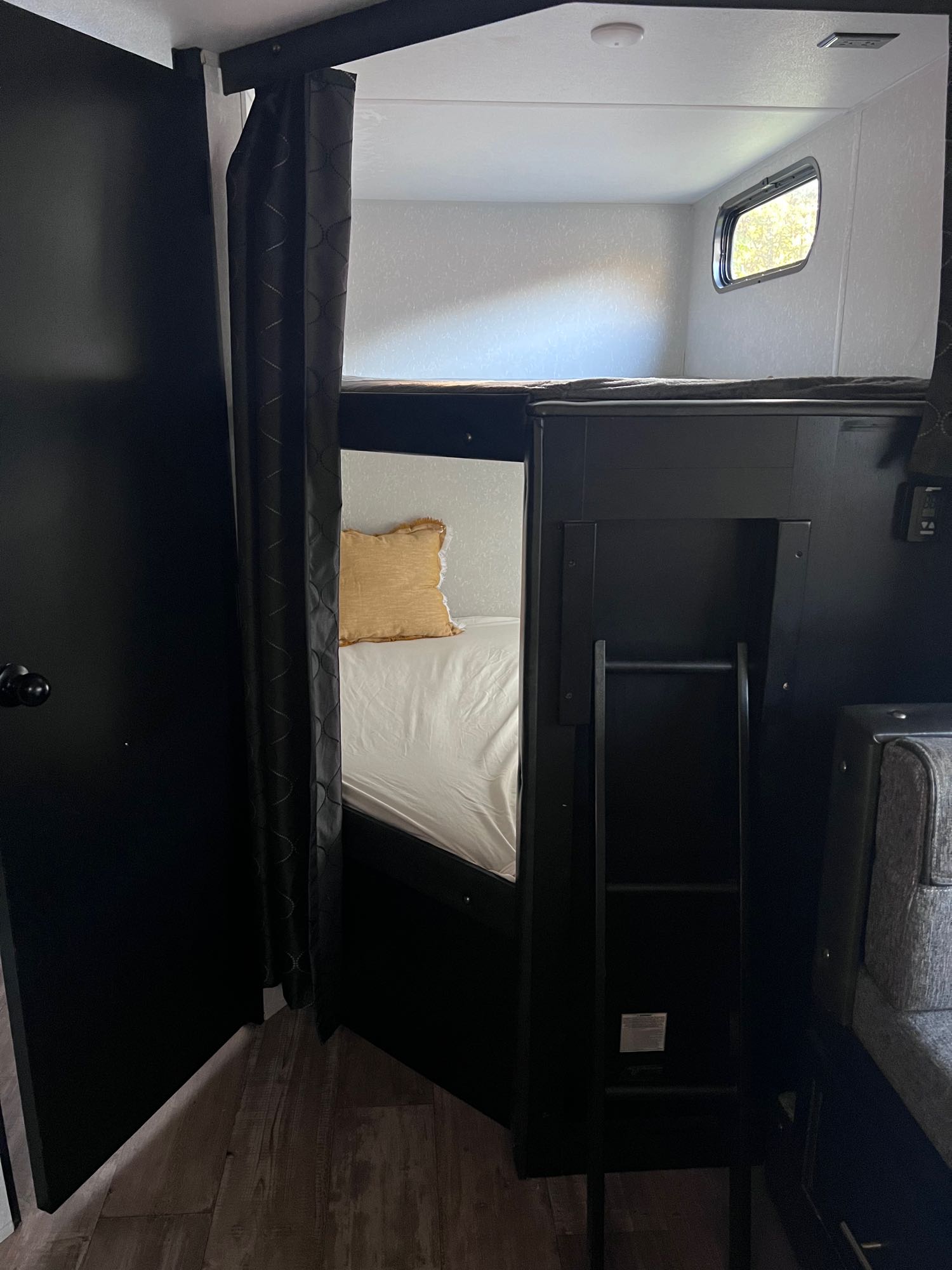 Cozy rv rental interior featuring dark bunk beds with privacy curtains, a window, and a ladder for easy access.. Forest River Cherokee Grey Wolf Black Label 2021