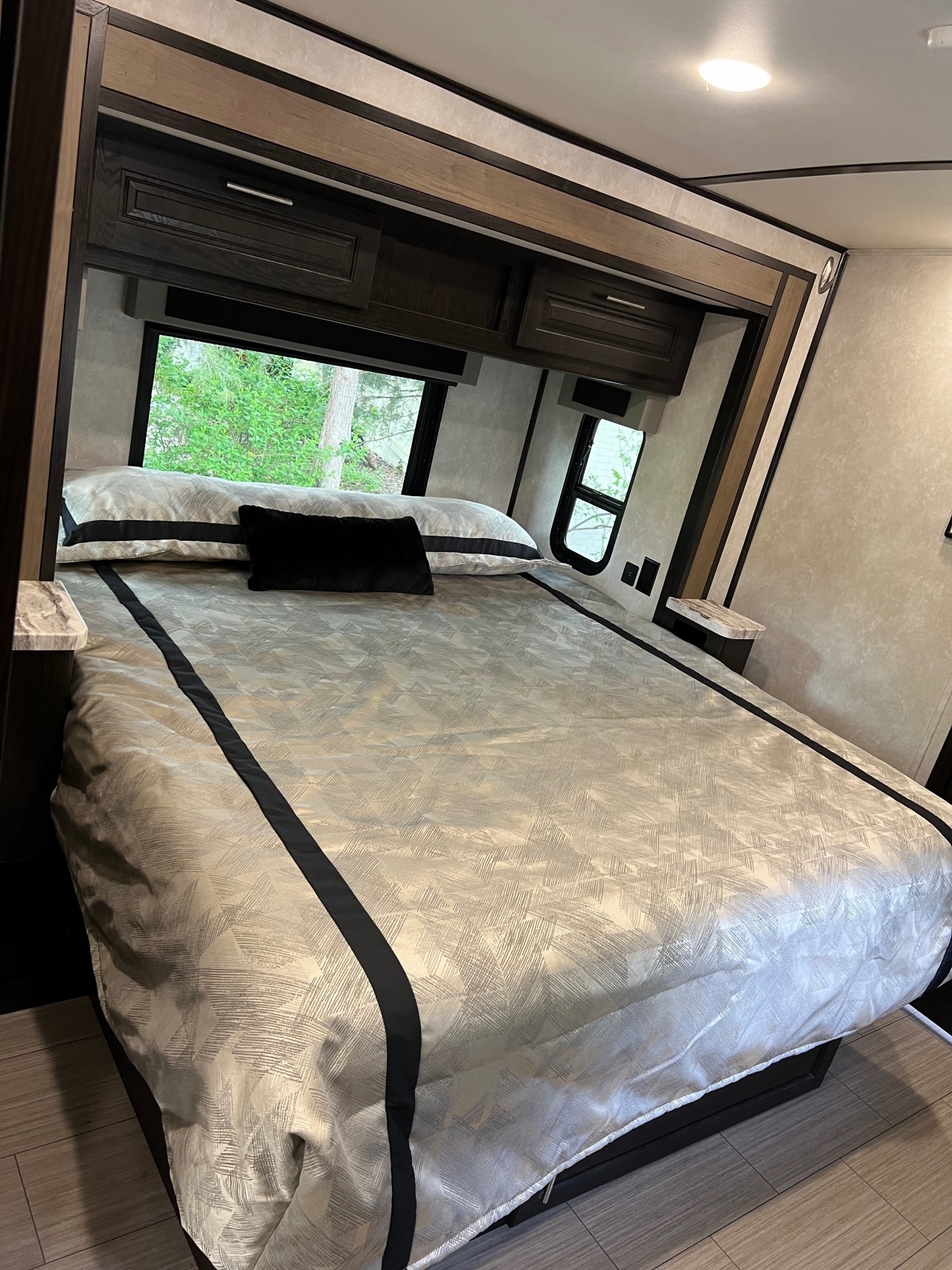 Modern RV rental bedroom with a large bed, overhead storage, and scenic windows. Enjoy comfortable travel accommodations.. Forest River Fr3 2020
