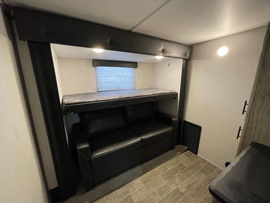 Cozy RV rental interior with bunk bed over convertible sofa, providing extra sleeping space.. Forest River Cherokee Arctic Wolf 2022