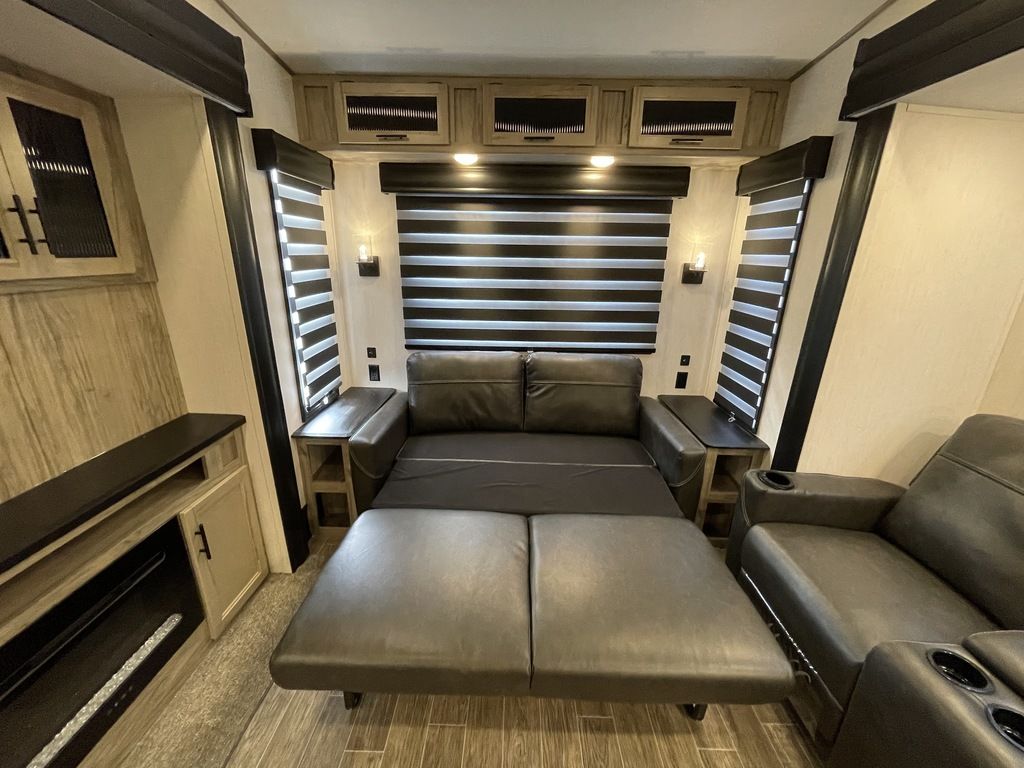 Spacious RV rental living area featuring a pull-out sofa bed, recliners, and warm ambient lighting.. Forest River Cherokee Arctic Wolf 2022