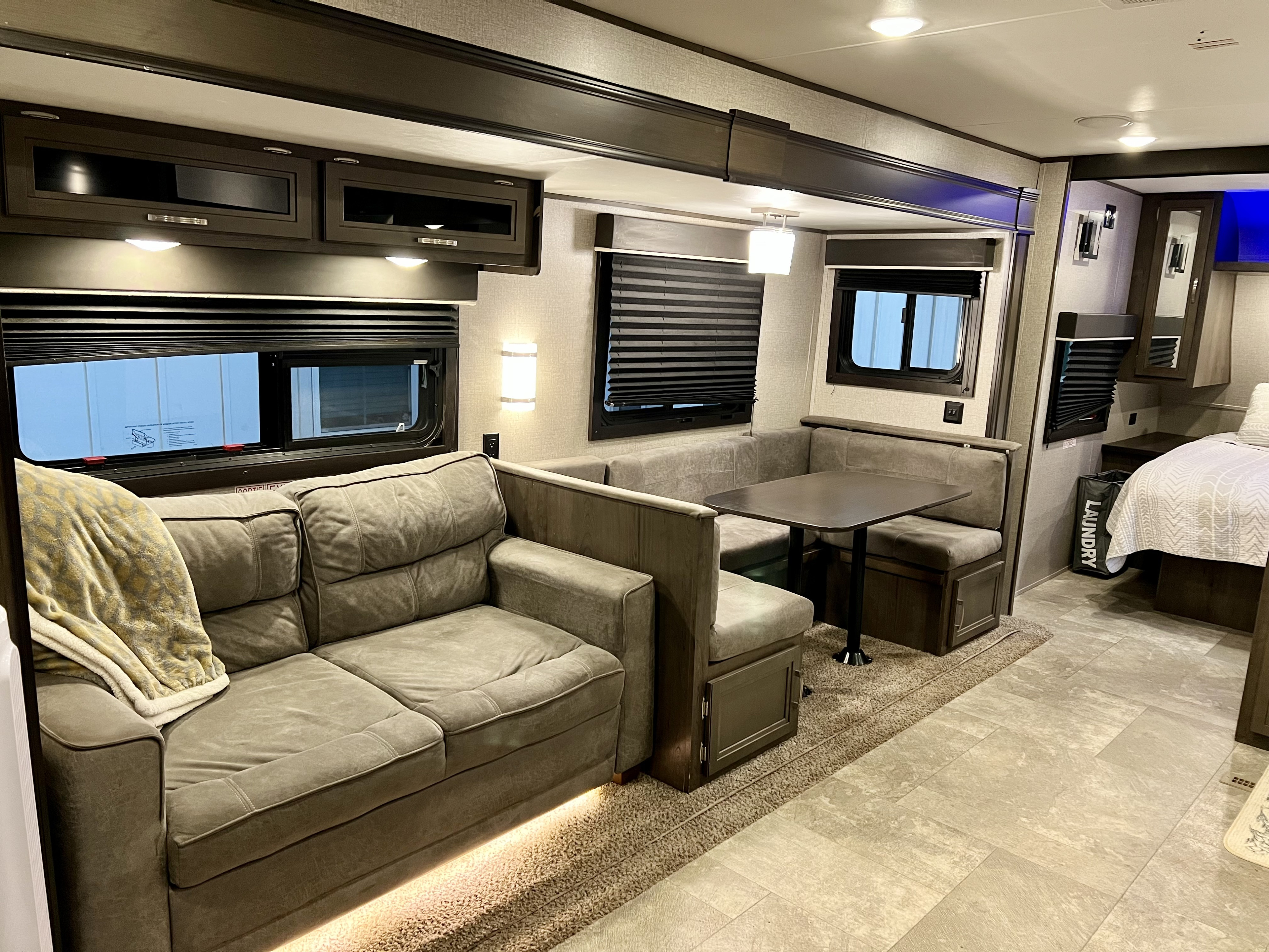 View inside an RV rental, showcasing a comfortable living area with a plush sofa, dining booth, and modern overhead cabinets.. Jayco Jay Flight 2020