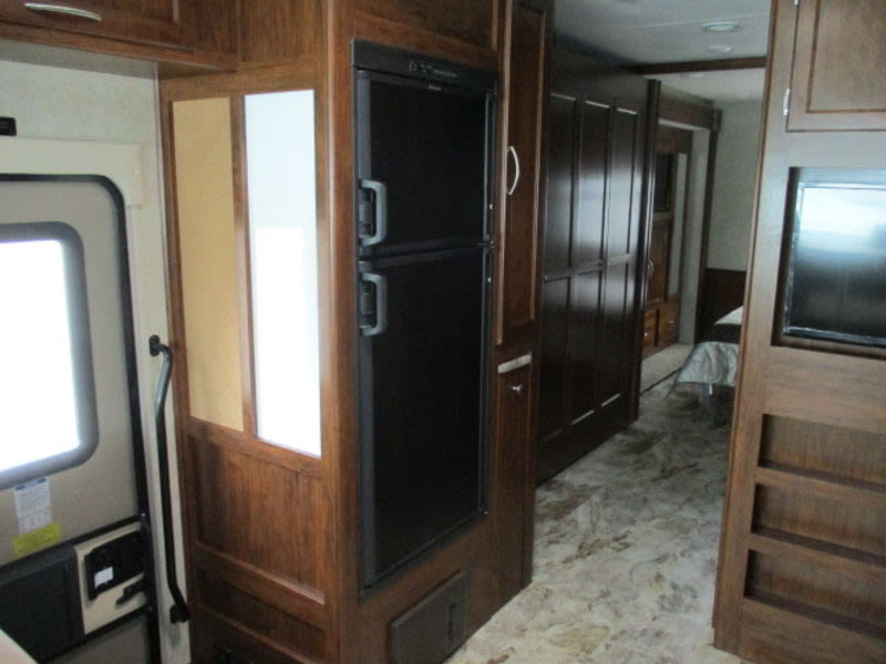 RV rental interior: Kitchen/living area with fridge, wood cabinets, and hallway leading to bedroom. Spacious.. Forest River Coachmen Pursuit 2017