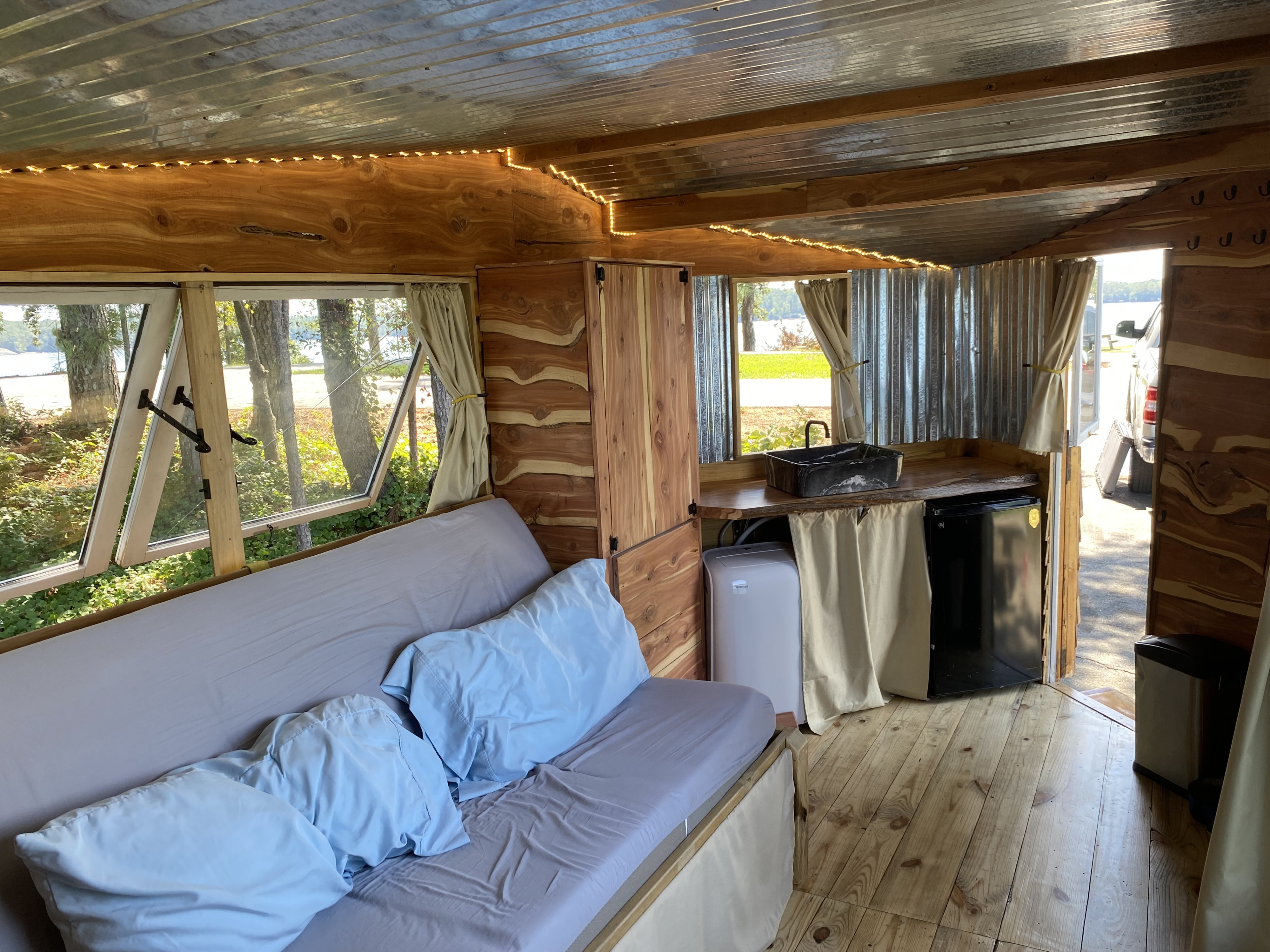 Inside a unique **RV rental**: enjoy rustic wood, metal walls, warm lights, and a kitchen with beautiful lake views.. Tiny House On Wheels Glamper / Glamping Trailer THOW Tiny House On Wheels Glamper / Glamping Trailer THOW 2023