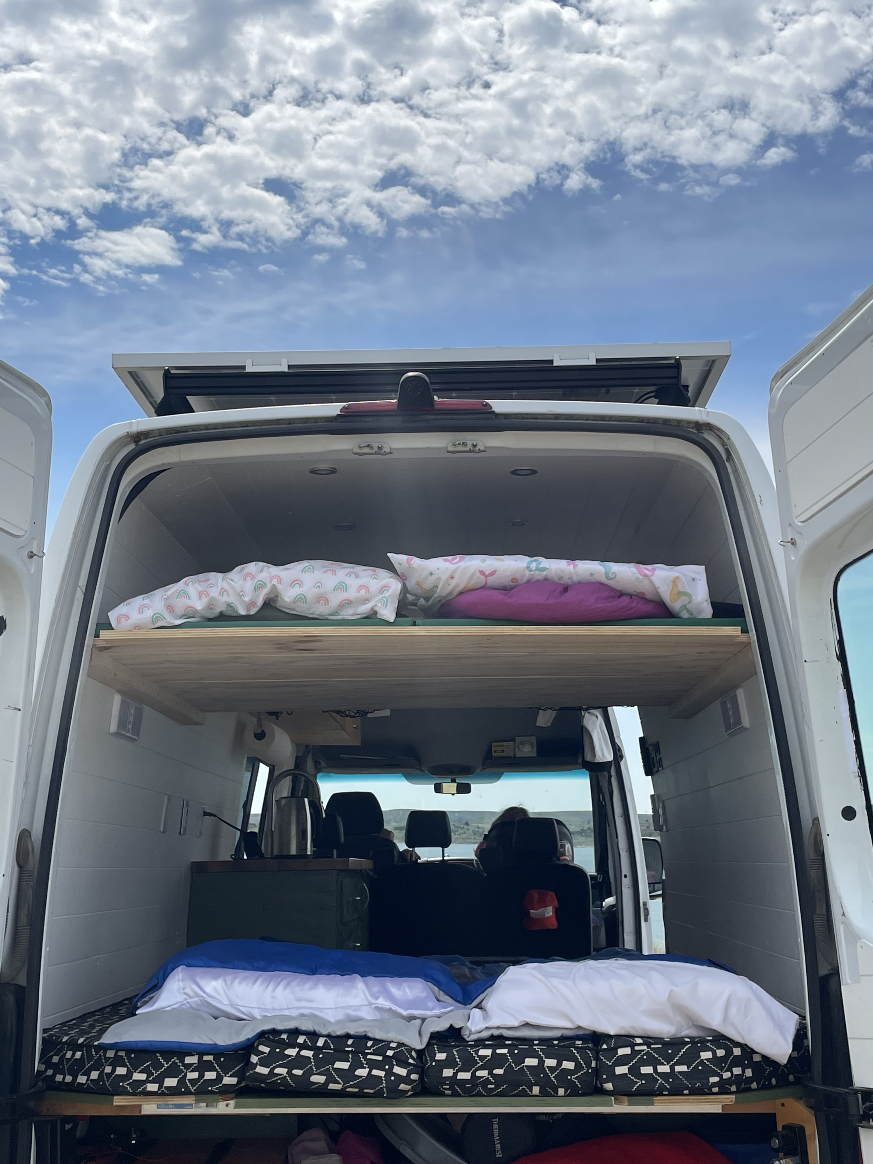 An RV rental setup: a white Ram truck tows a Mallard travel trailer on a scenic dirt camp path.. Mercedes-Benz Sprinter 2013