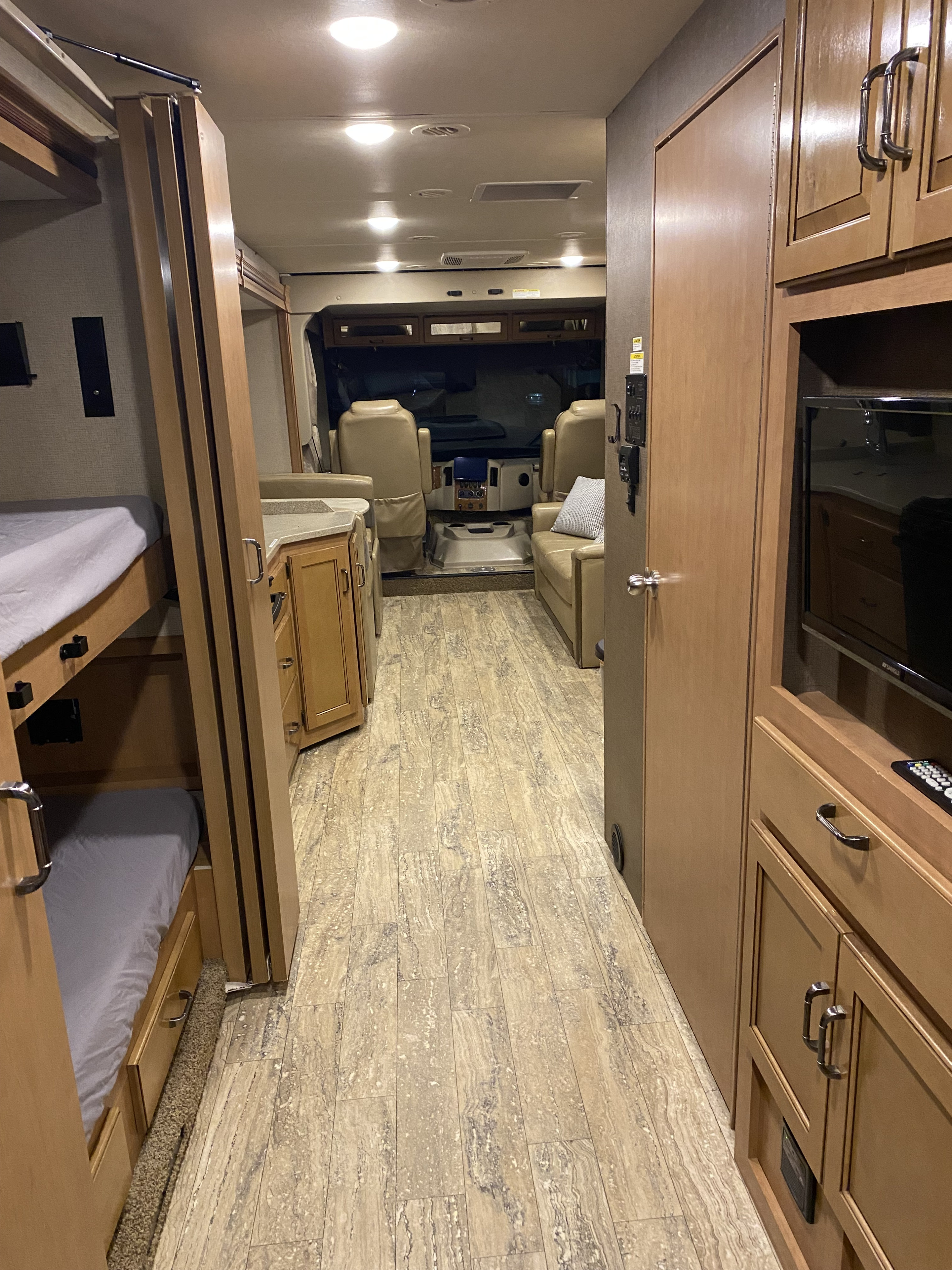 RV rental interior: View from rear showing bunk beds, living area with TV, and forward cockpit seating area.. Thor Hurricane 2017