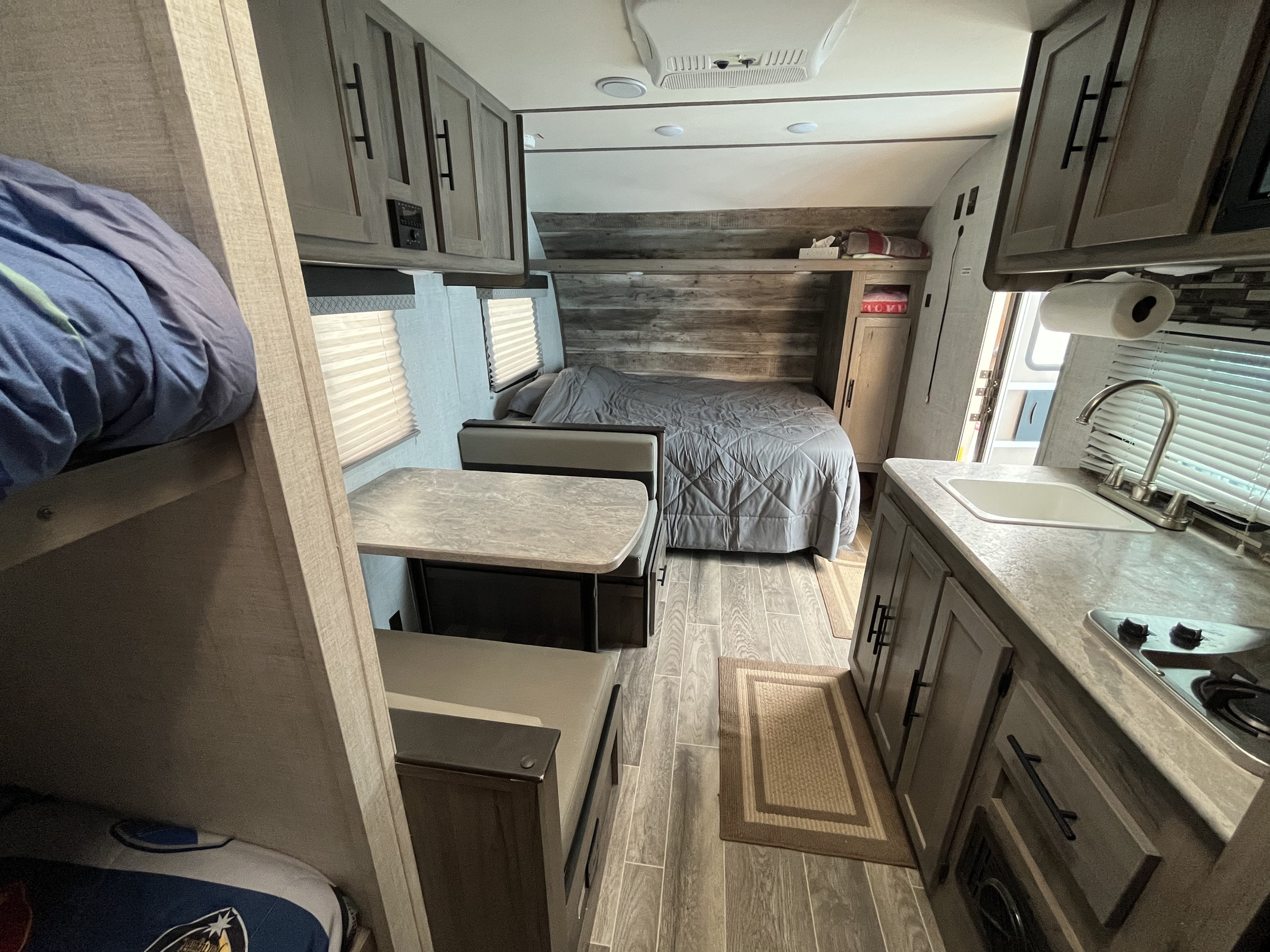 Spacious RV rental interior featuring a bed, bunk bed, dinette, and kitchen area, perfect for travel comfort.. Gulf Stream Ameri-Lite Super Lite 2022