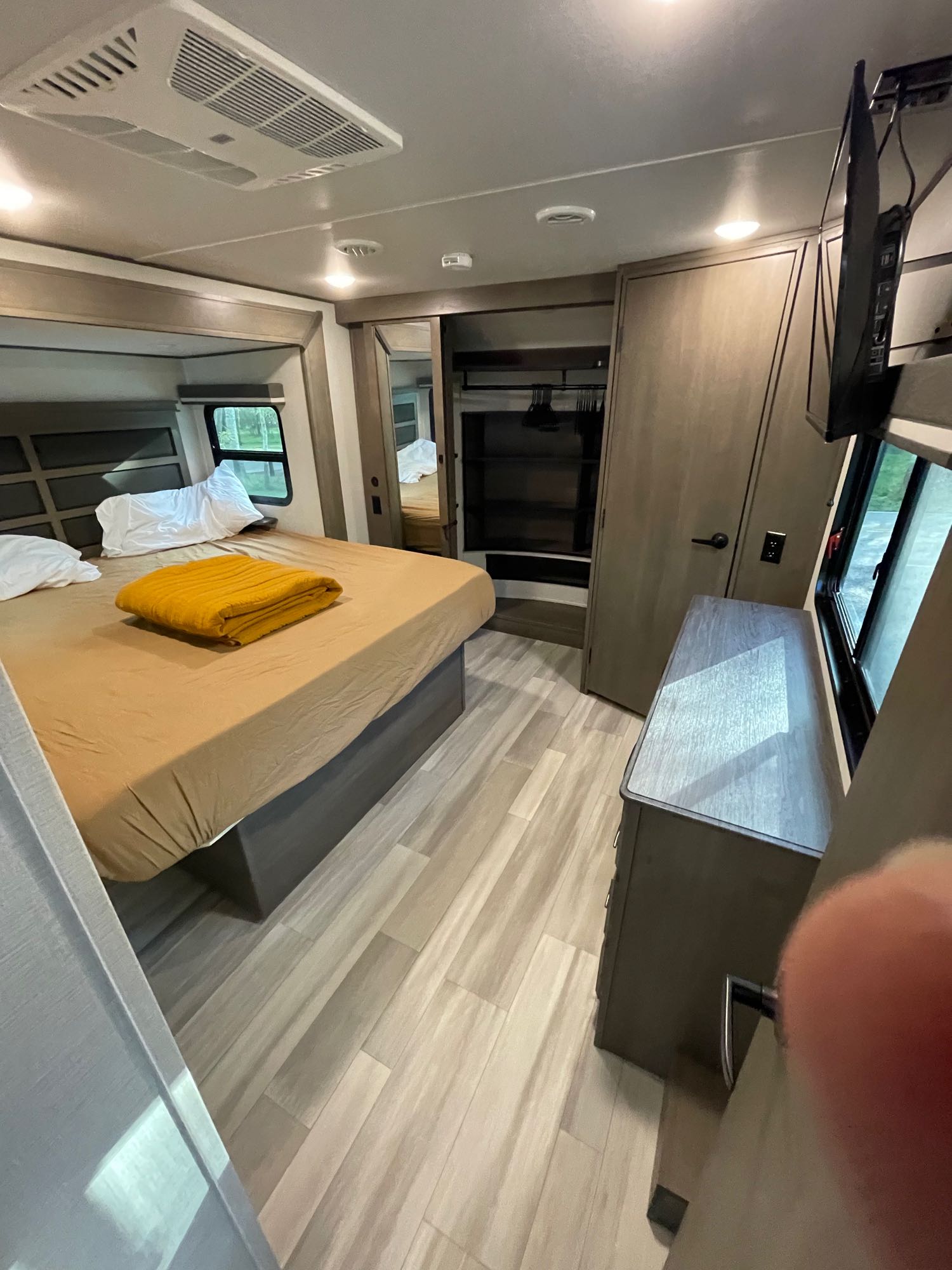 Modern rv rental bedroom featuring a comfortable bed, TV, wardrobe, and window. Your cozy home on wheels awaits!. Grand Design Solitude S-Class 2023