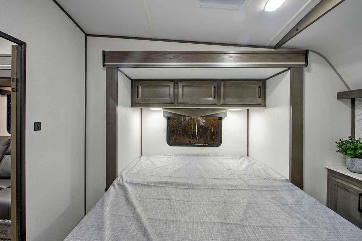 Cozy RV rental bedroom featuring a comfortable bed, overhead cabinets, and a window. Ideal for compact travel.. Cruiser Rv Corp Stryker 2022