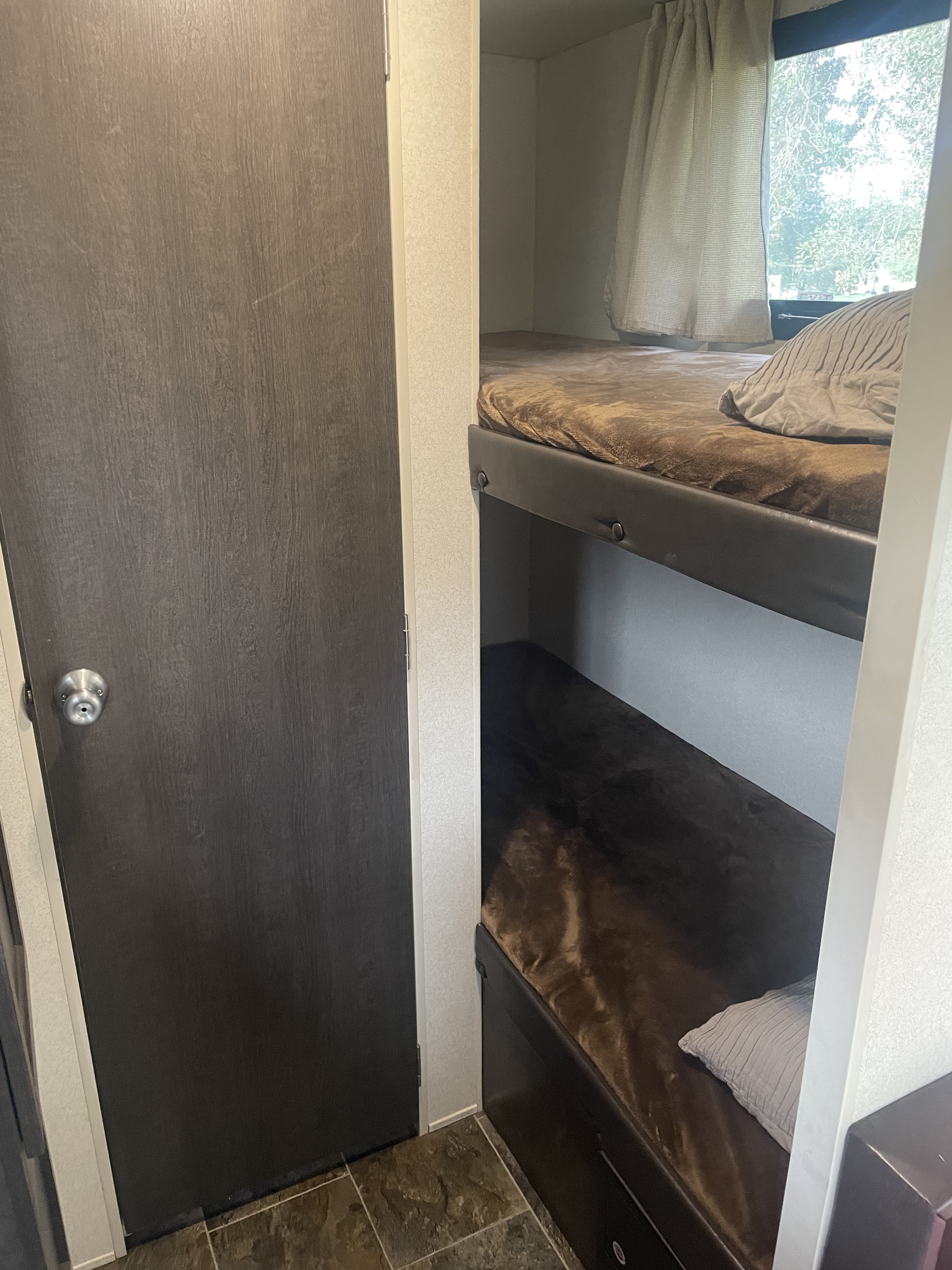 RV rental's compact interior with comfortable bunk beds, a window offering outdoor views, and a door.. Forest River Other 2019
