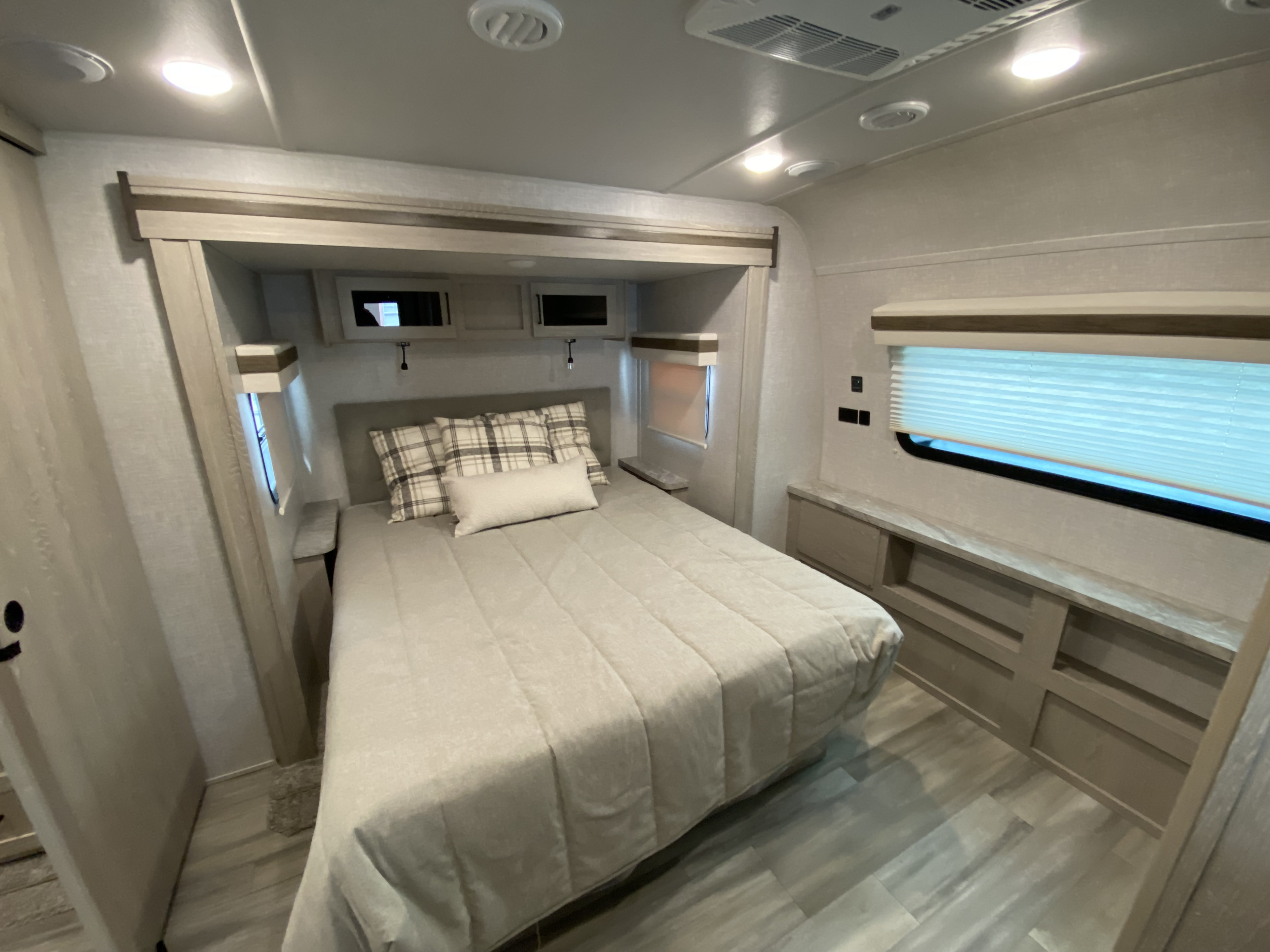 This inviting RV rental bedroom offers a comfortable bed, overhead cabinets, and built-in storage, ideal for compact travel.. Forest River Rockwood 2023