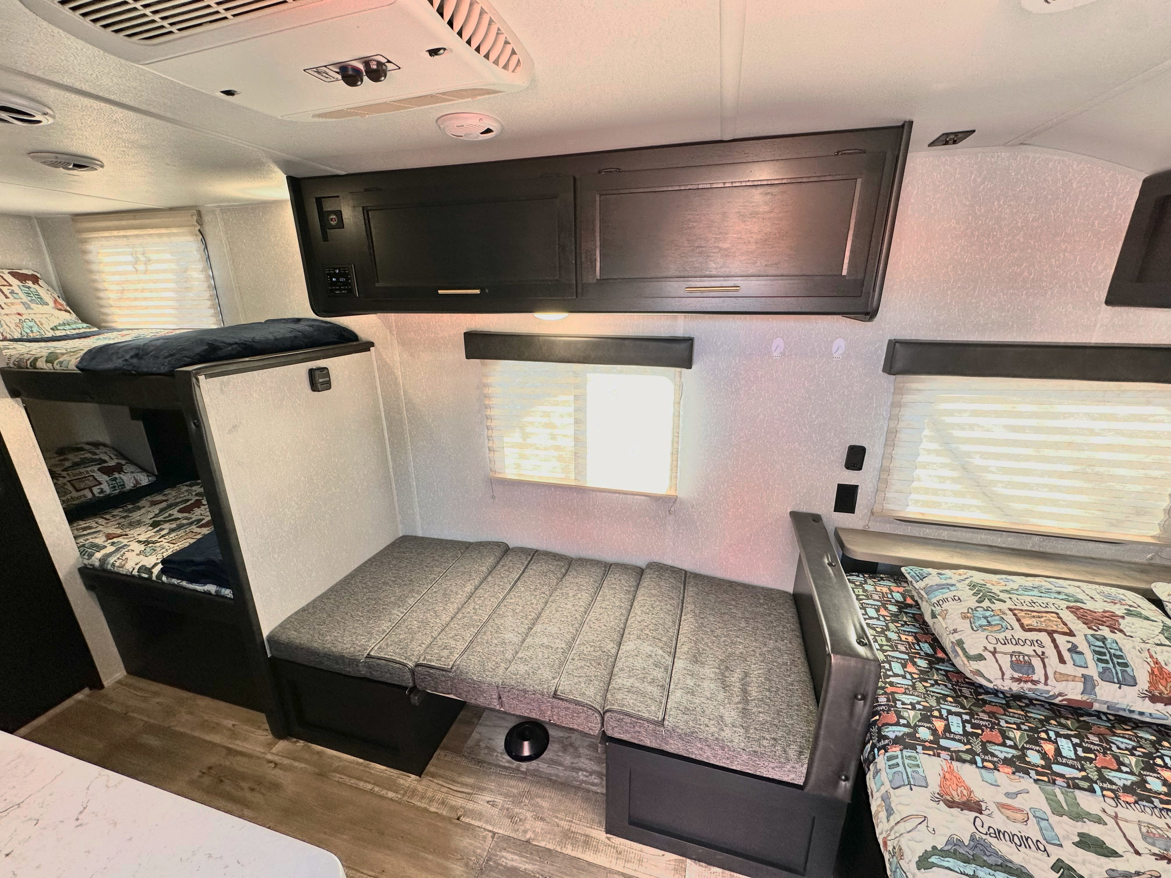 Cozy RV rental interior showcasing bunk beds and a dinette that converts to a bed, adorned with nature-themed bedding.. Forest River Cherokee Wolf Pup 2021