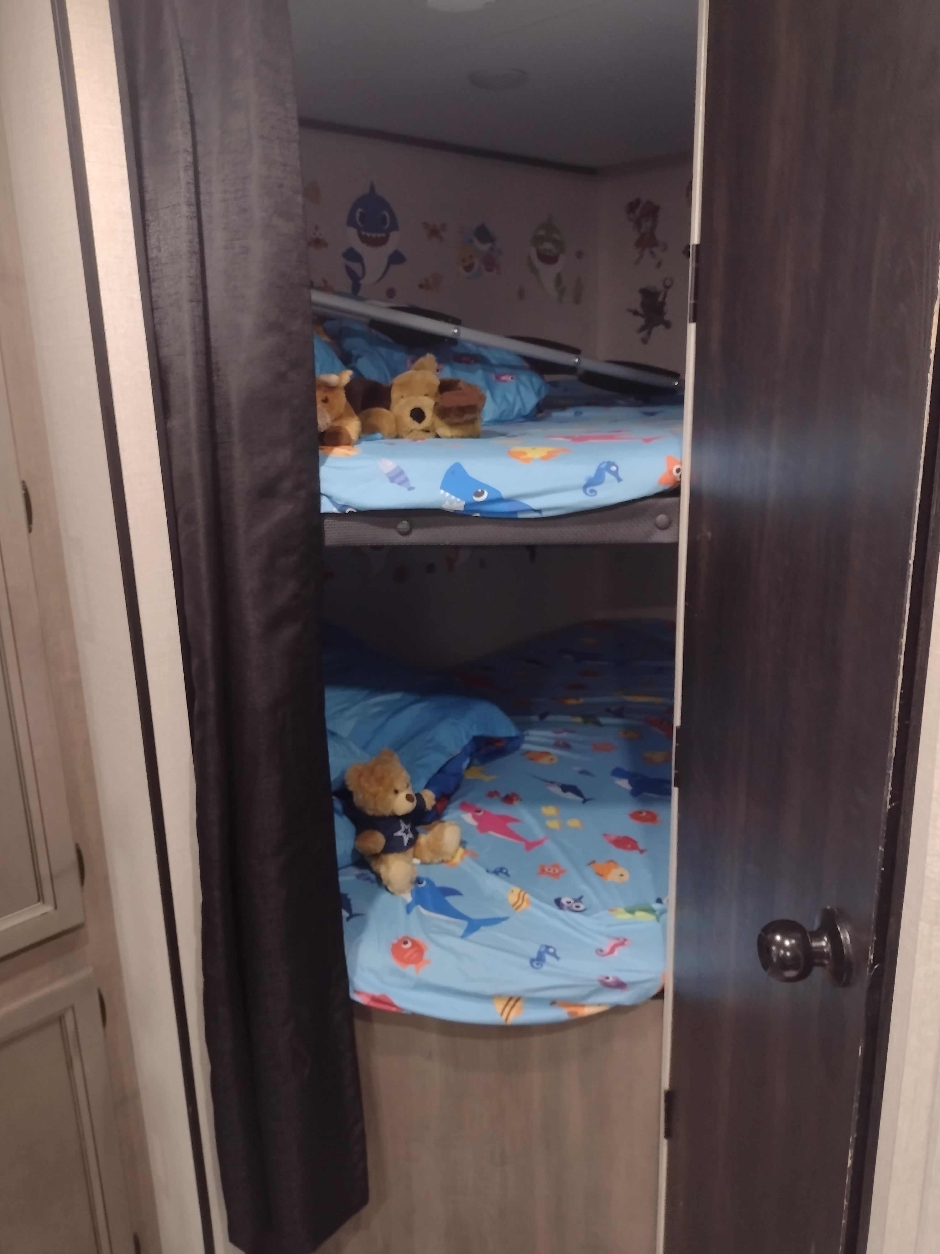 Cozy bunk beds in an RV rental, featuring blue bedding with sea creatures and stuffed animals. Perfect for kids on a trip.. Highland Ridge RV Olympia 2022