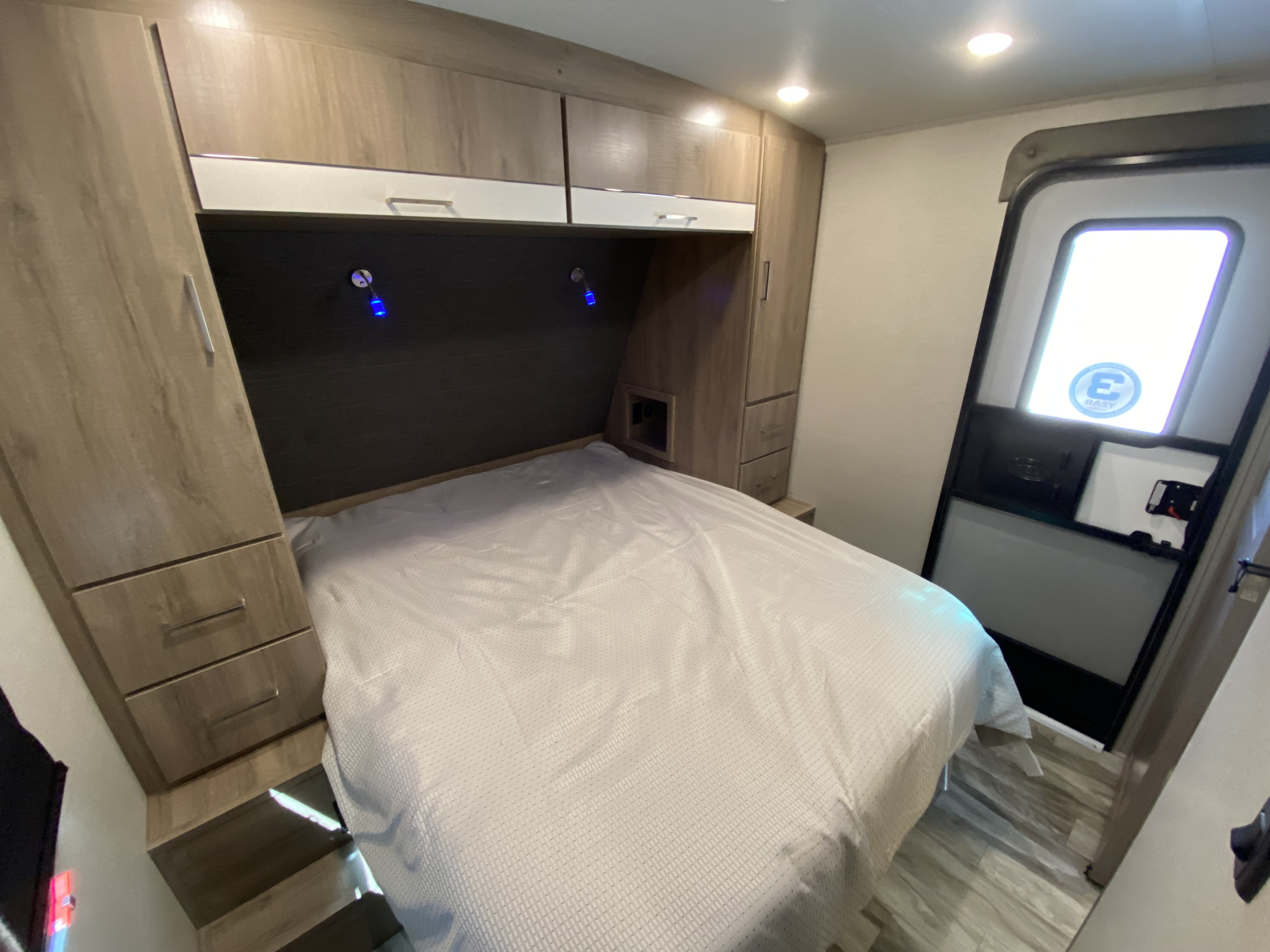 RV rental bedroom interior: cozy bed, overhead cabinets, and built-in storage. Ideal for comfortable travel.. Grand Design Imagine 2022