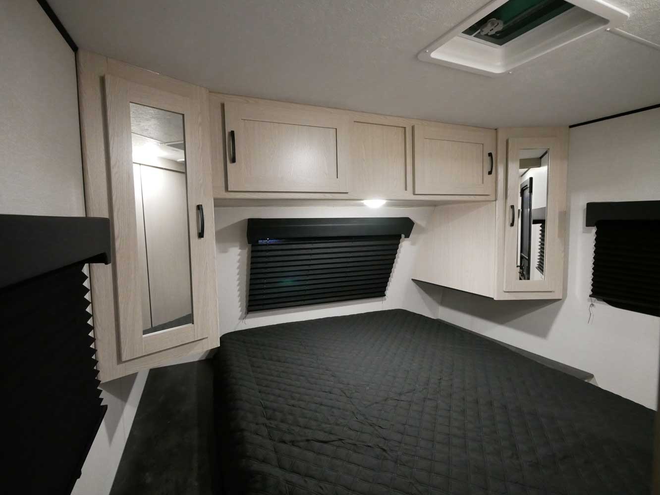 RV rental bedroom with a quilted bed, overhead storage, mirrored closets, and window blinds.. Coachmen Apex 2021