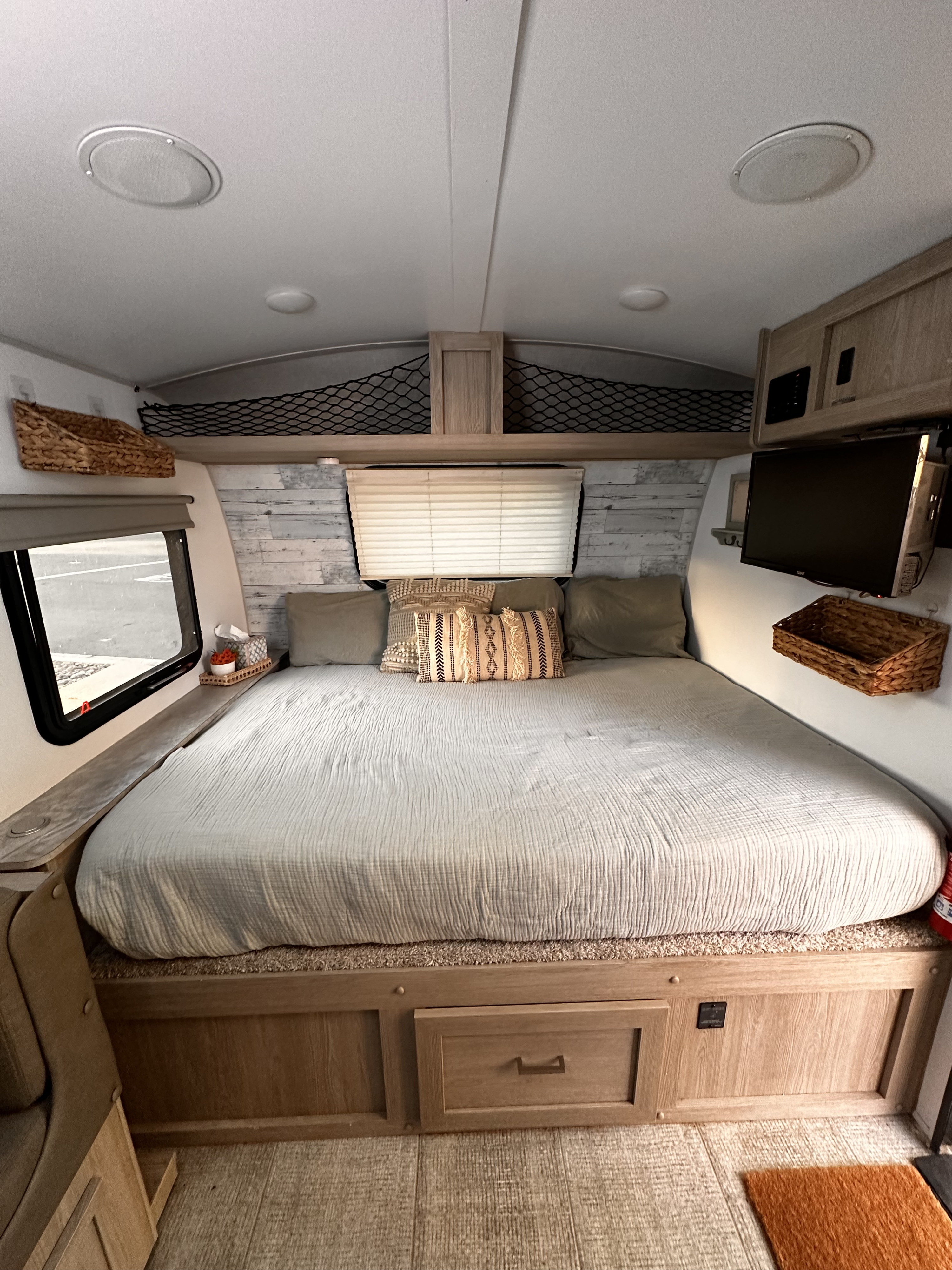 Cozy RV rental bedroom featuring a large bed, built-in storage, wall-mounted TV, and charming decor for a comfortable stay.. Forest River Rockwood Geo Pro 2021