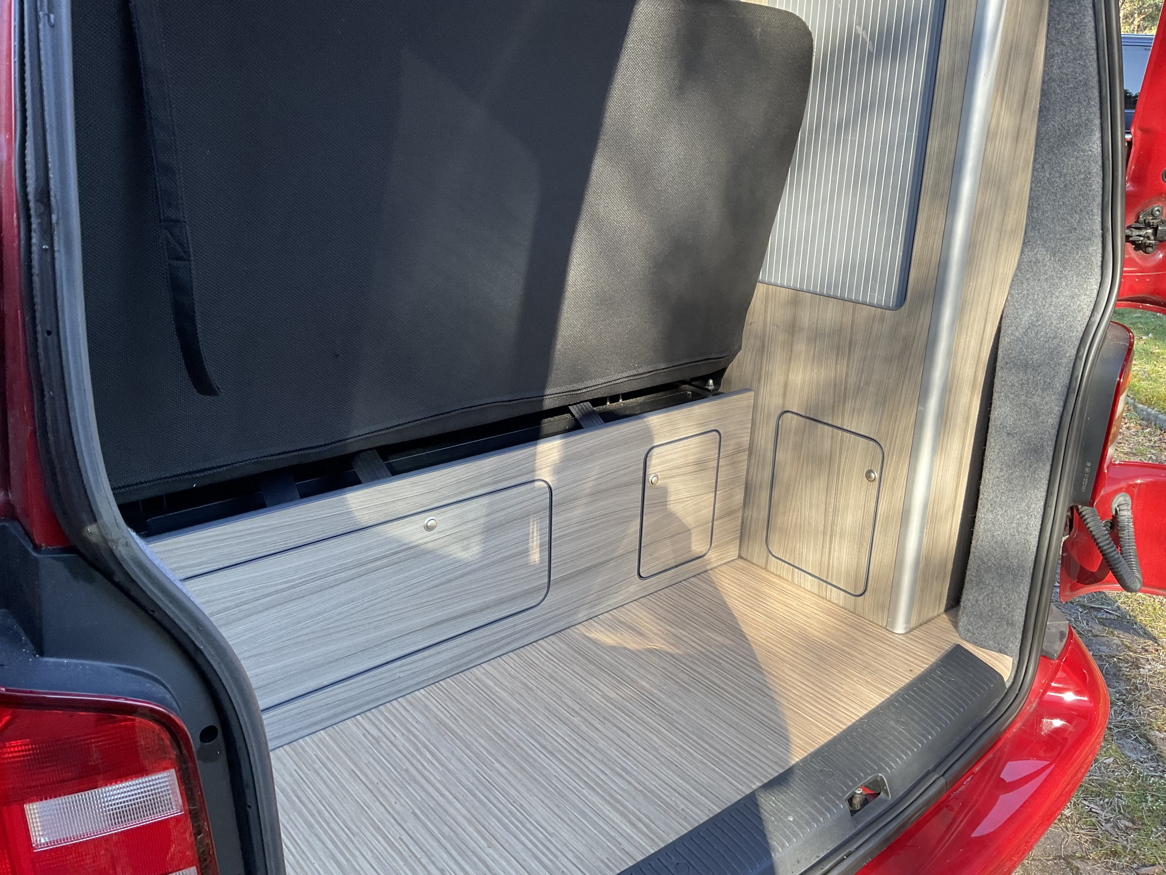 RV rental: Modern camper interior with a black bench/bed, wood-look flooring & integrated storage cabinets.. Volkswagen Transporter Stratherrick 2017