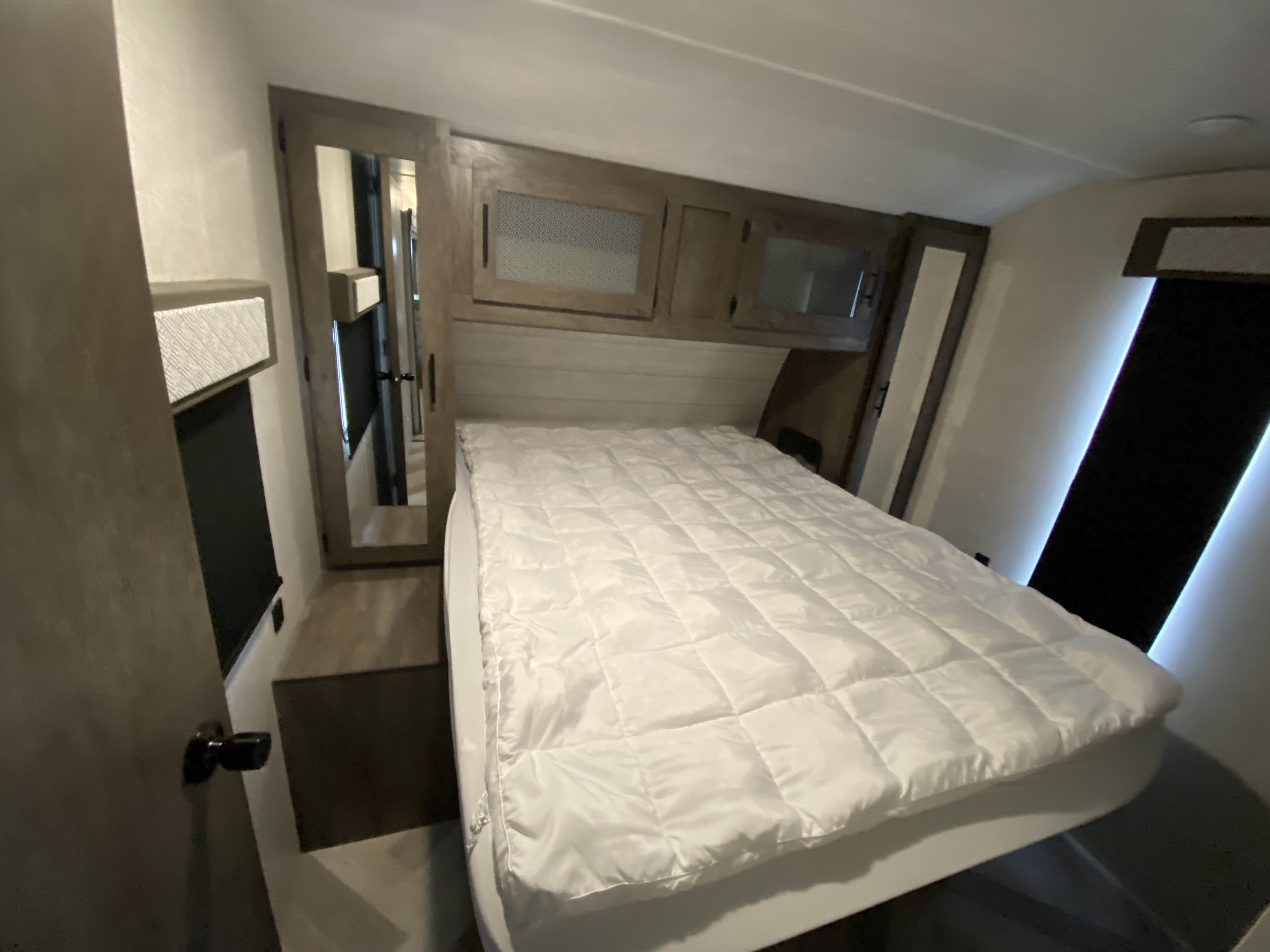 Cozy RV rental bedroom featuring a comfy bed, overhead storage, and mirrored closets. Ideal for travel adventures.. Forest River Salem 2021