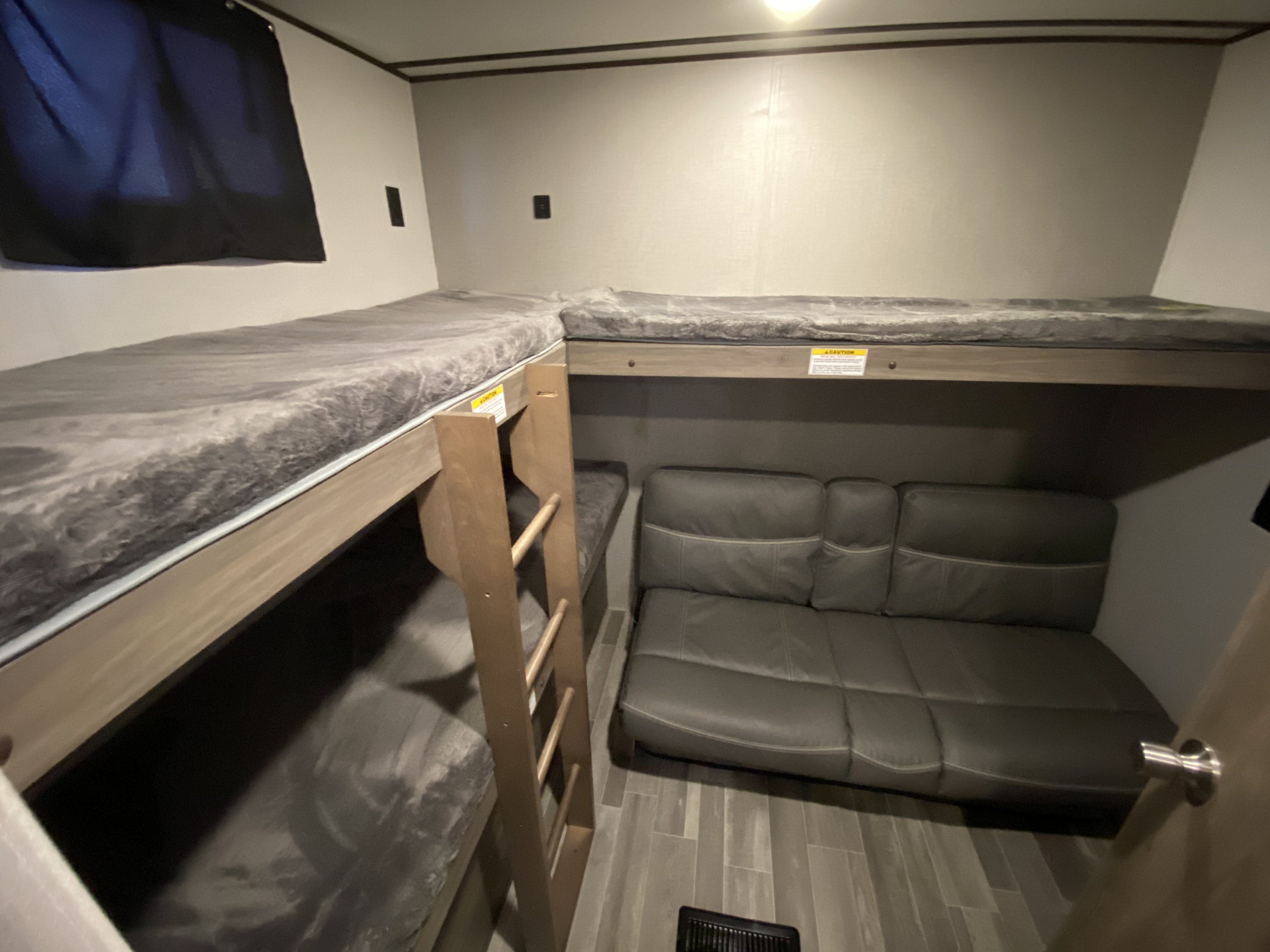 RV rental interior featuring practical bunk beds, a comfortable sofa, and wood-look flooring for a versatile space.. Keystone Crossroads Zinger 2021