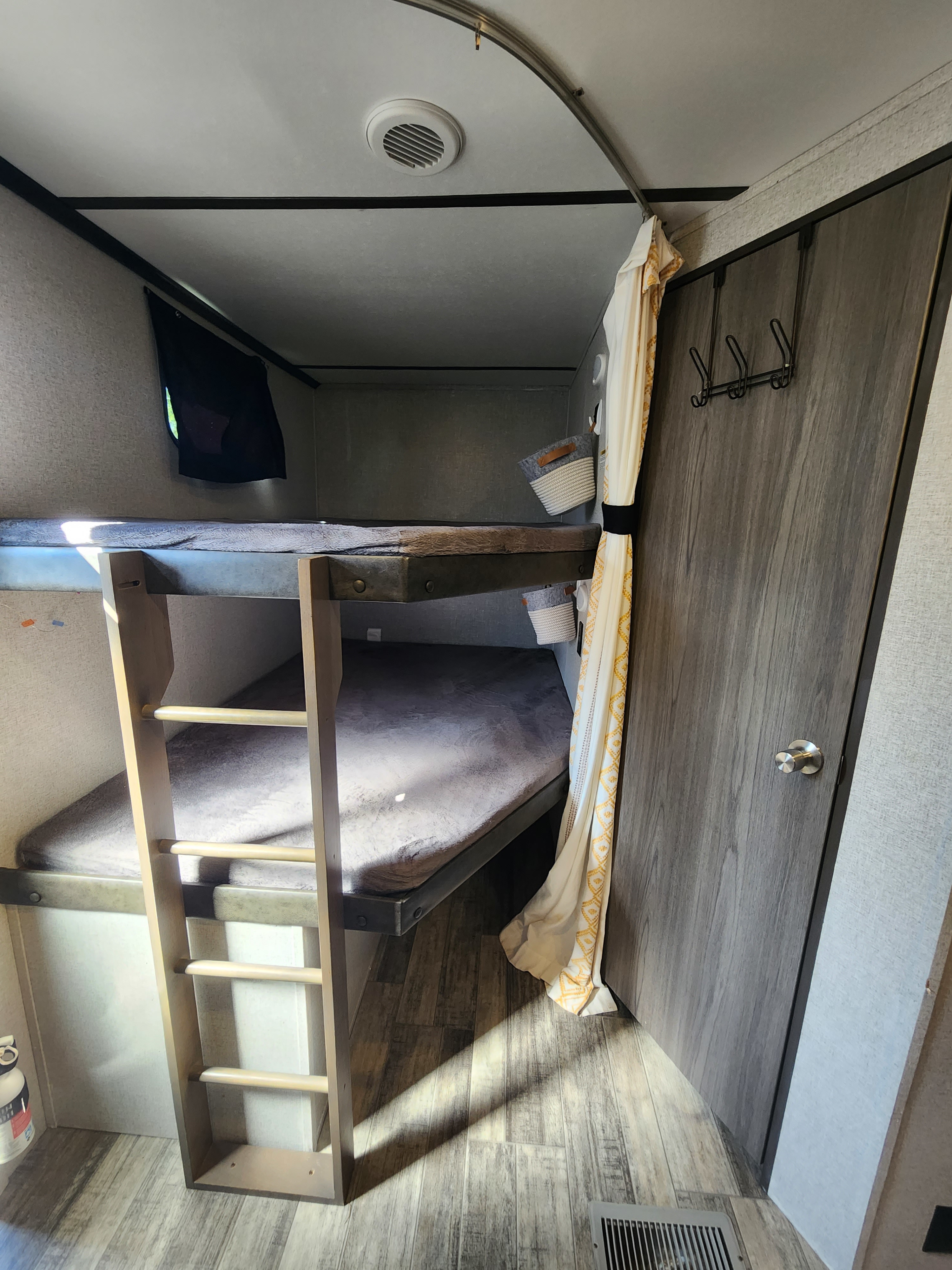 Cozy RV rental bunk beds with ladder, curtain, and storage baskets, ideal for family travel.. Crossroads Volante 2020