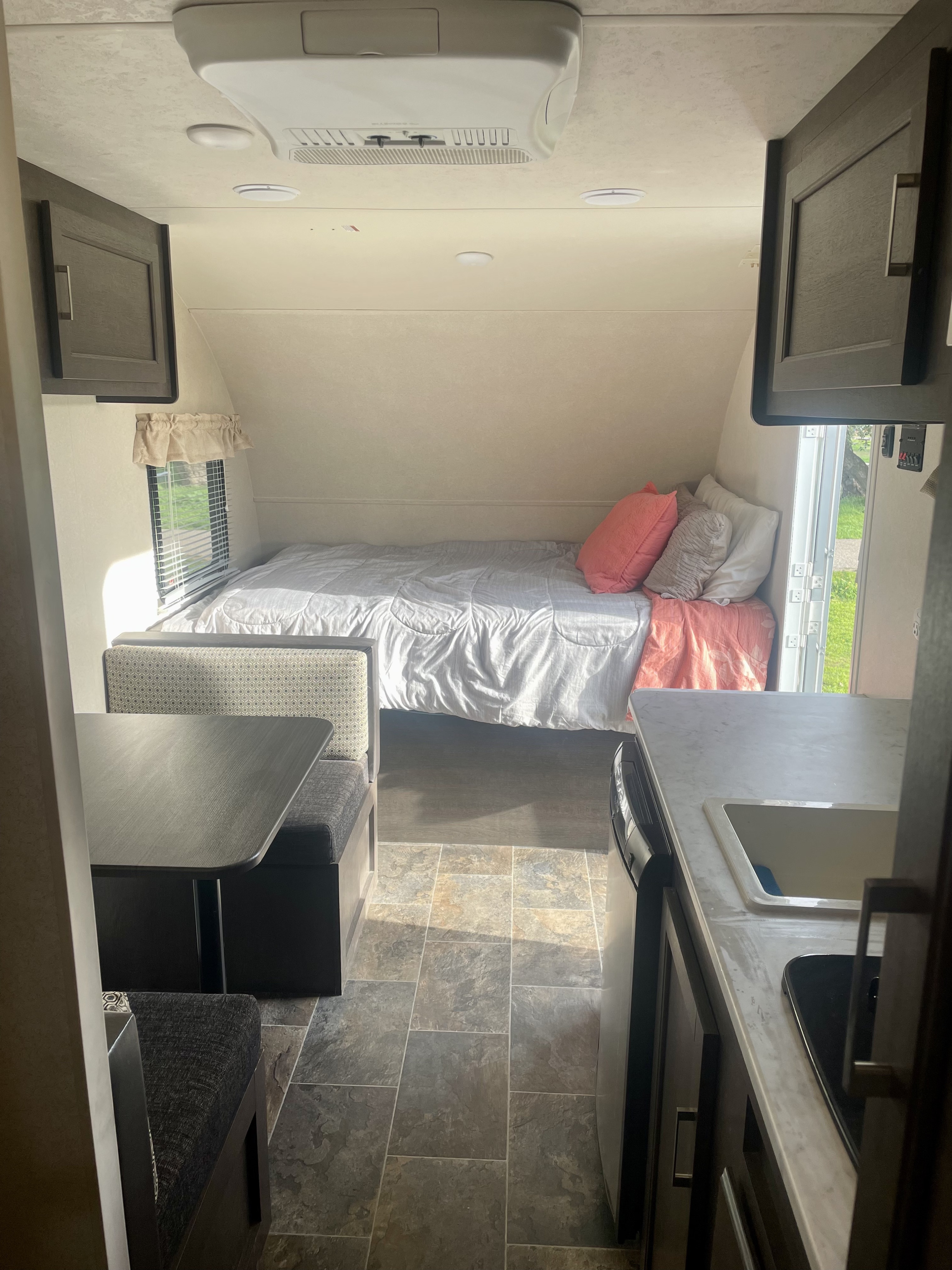Step inside this RV rental, featuring a cozy bed, dinette with patterned seats, and a compact kitchen area.. Forest River Other 2019