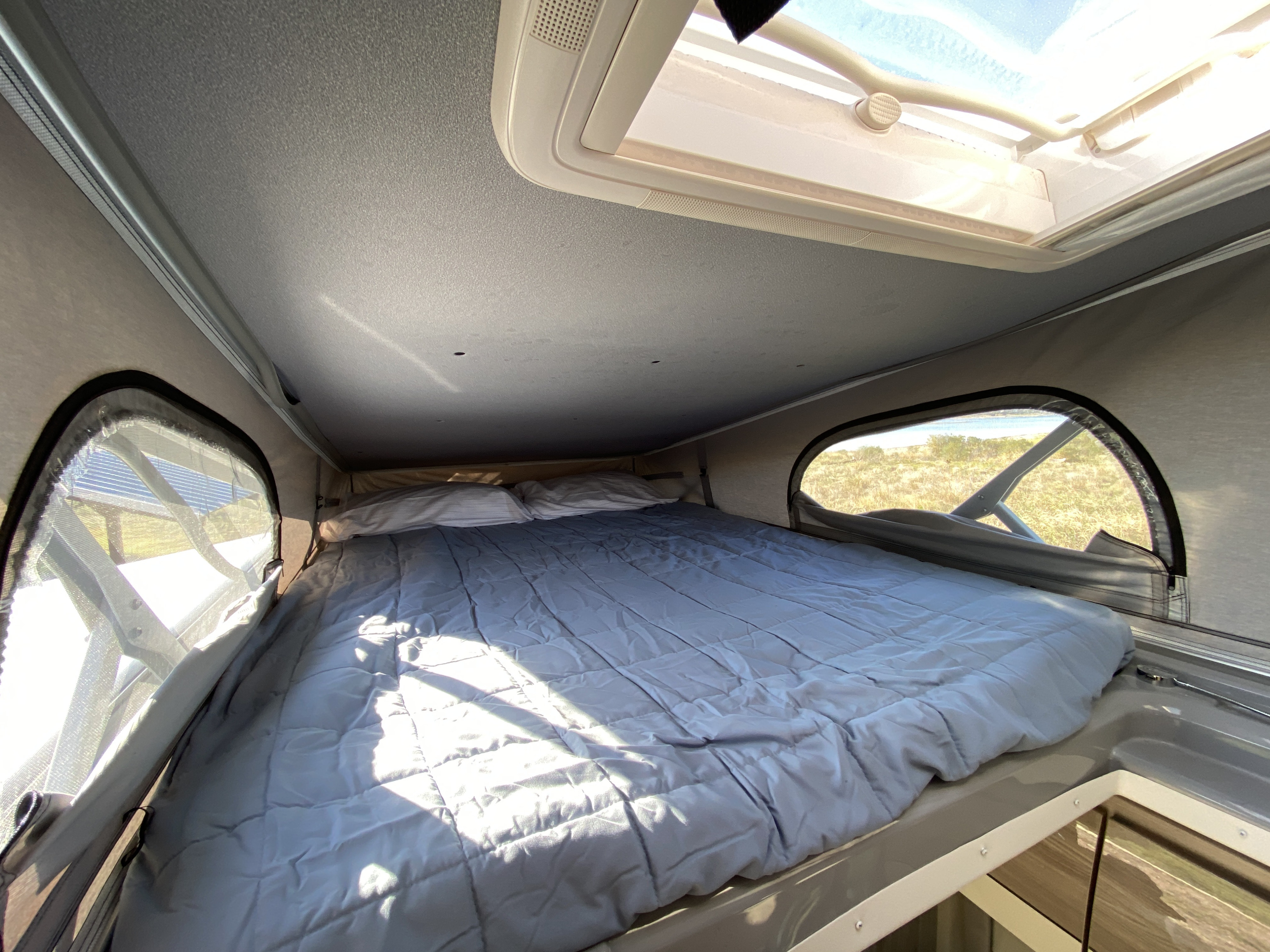Relax in this cozy RV rental bed area with a bright skylight and panoramic views, great for your next adventure.. Thor Sequnce 2023