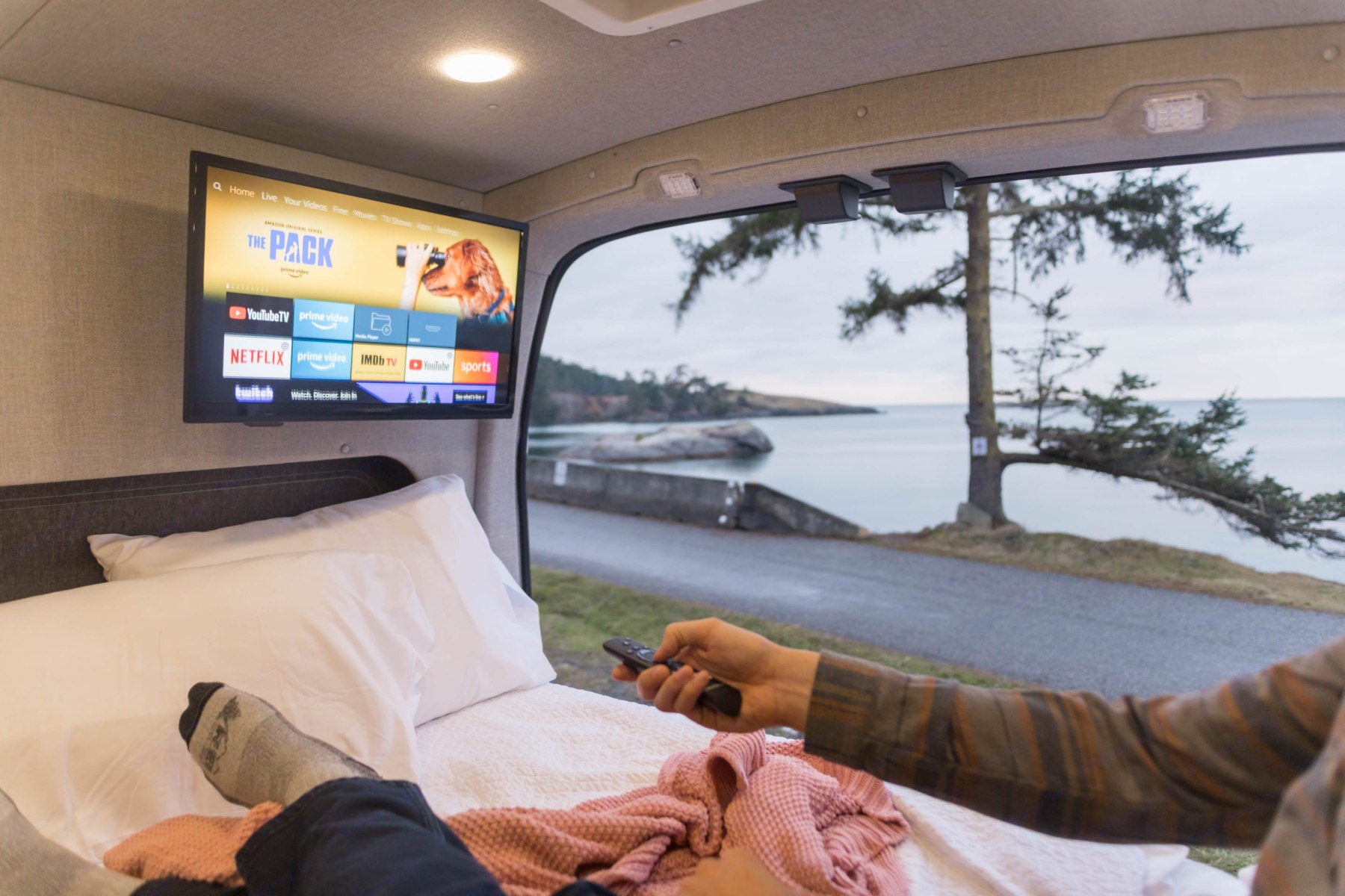 Relaxing in a cozy RV rental with a scenic view, enjoying TV. Perfect mobile entertainment on the go.. Ford Transit 2022